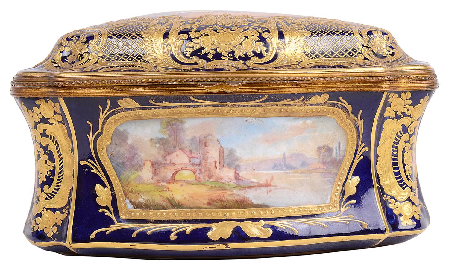 A good quality 19th century French porcelain 'Sevres' style porcelain casket. Having cobalt blue borders with gilded scrolling decoration. Inset painted panels, depicting a romantic and rural scenes. The lid opening to reveal a velvet lined
