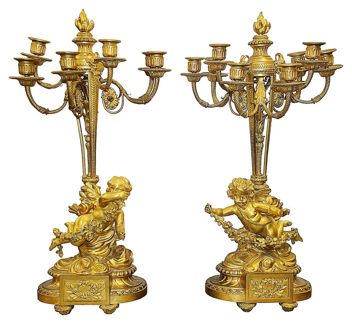 A very impressive 19th century gilded ormolu Louis XVI style clock garniture. The clock having four cherubs amongst clouds surrounding it, with floral swags. The movement has an eight day, hour and half hour striking movement. The pair of