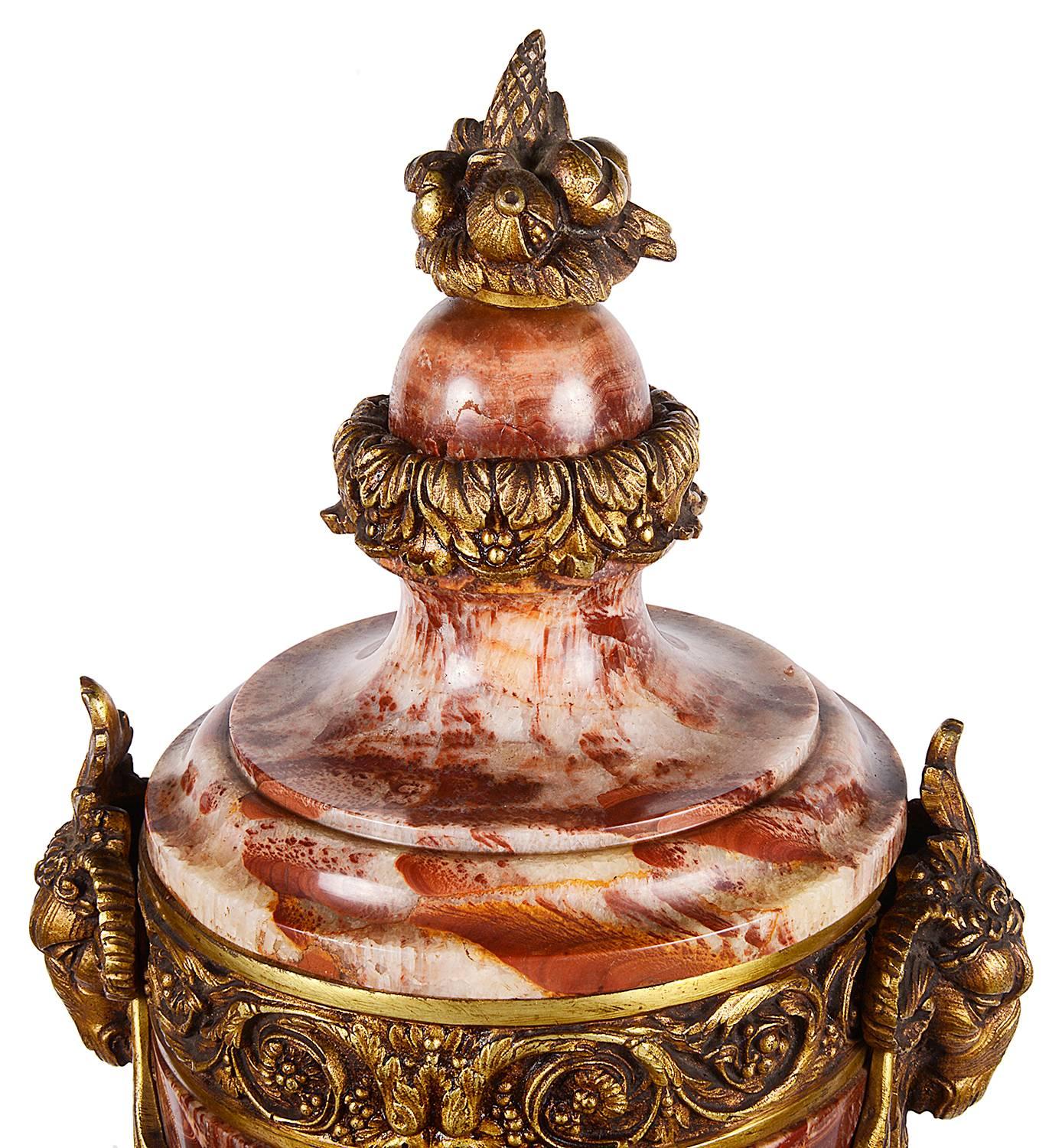 A good quality pair of French marble and gilded ormolu lidded urns. Rams head mounts to the side and scrolling foliate and swag decoration.