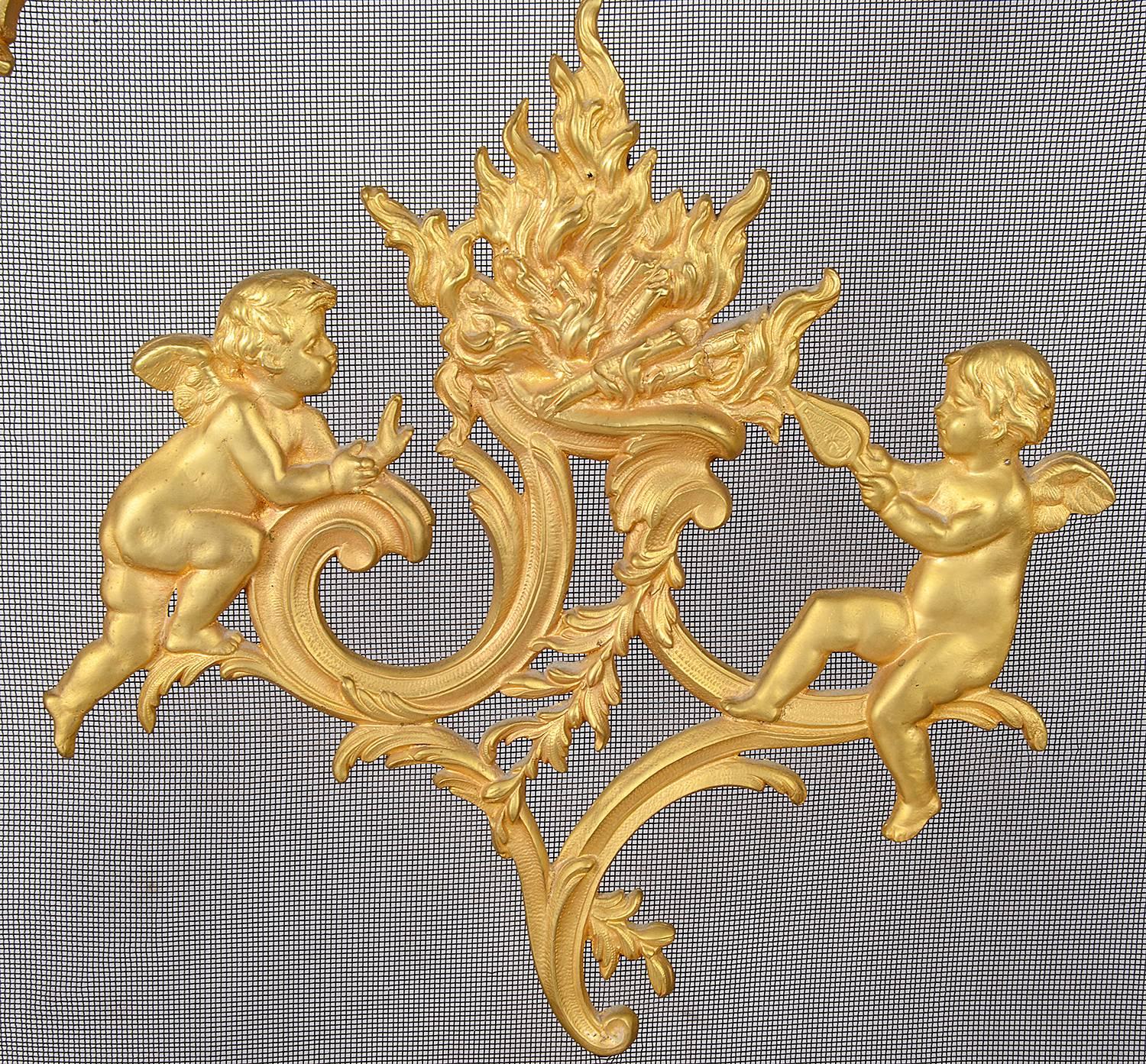 A good quality late 19th century French ormolu fire screen, in the Rococo style with scrolling foliate decoration, a flaming fire to the centre with a cherub either side.