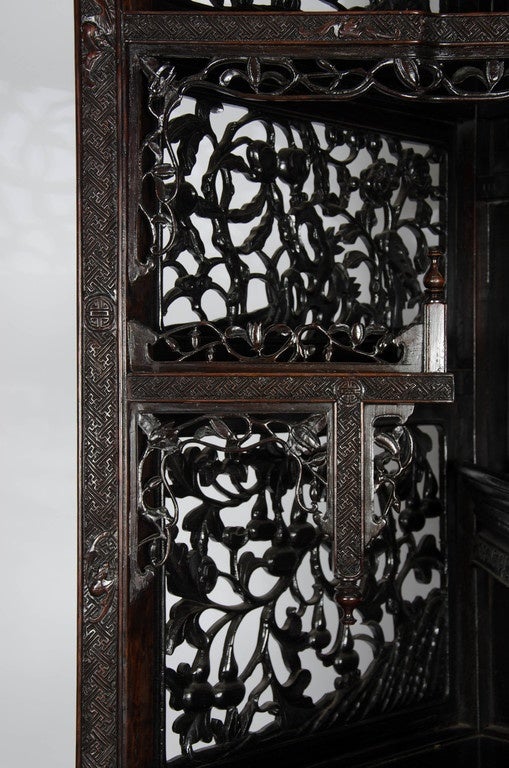 An unusual very good quality 19th Century Chinese hardwood corner cabinet with carved fretwork panels and decoration, raised on ball and claw feet.