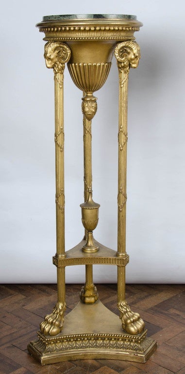 A good quality pair of carved giltwood Adam influenced marble-topped torchas. Having classical carved mouldings, Rams heads and claw feet raised on a plinth base.