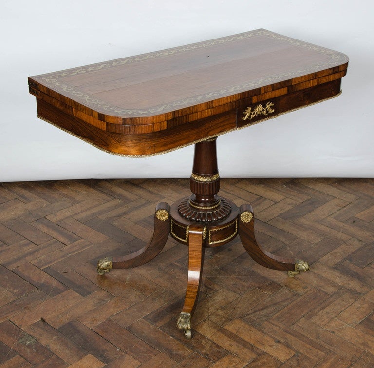 A good quality pair of Regency period Rosewood, brass inlaid card tables. with central turned pedestal, raised on four splay ormolu mounted legs, terminating in the original brass claw castors.