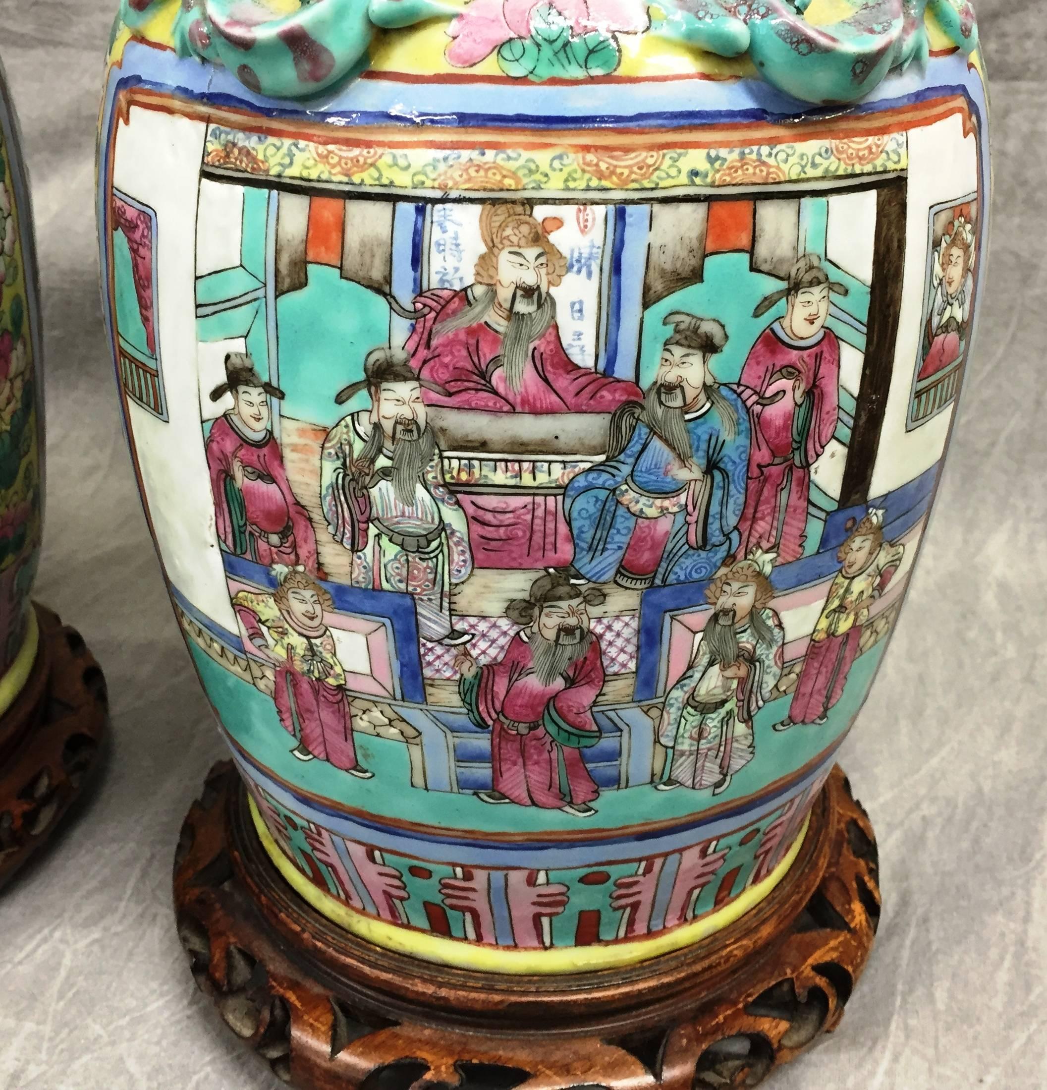 Paire de lampes tournées de bonne qualité, datant du 19ème siècle, en forme de vases de la famille rose. Les panneaux sont ornés de diverses scènes classiques et sont montés sur des supports en bois sculpté.