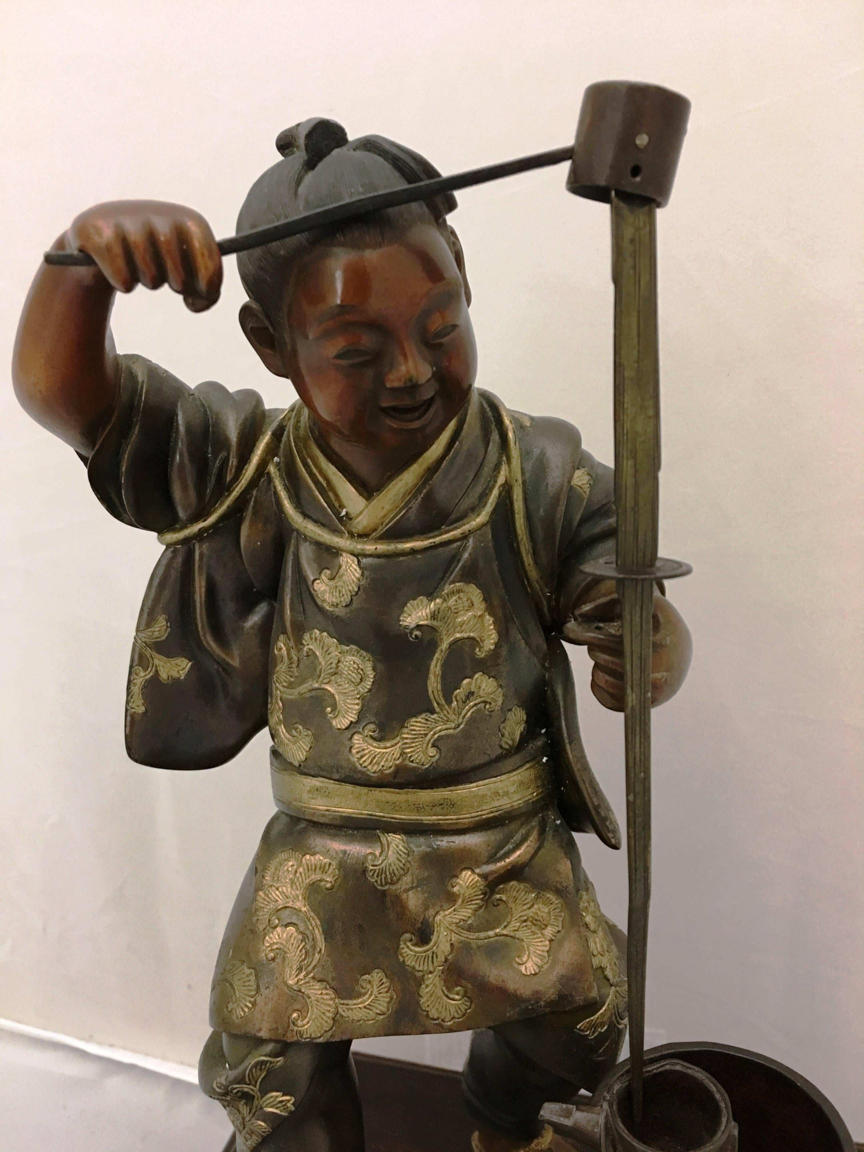 An enchanting 19th century Japanese Meiji period (1868-1912) bronze figure with gilded highlights of a man pouring liquid from one vessel to another. Signed on the back and mounted on a carved and gilded base.

  