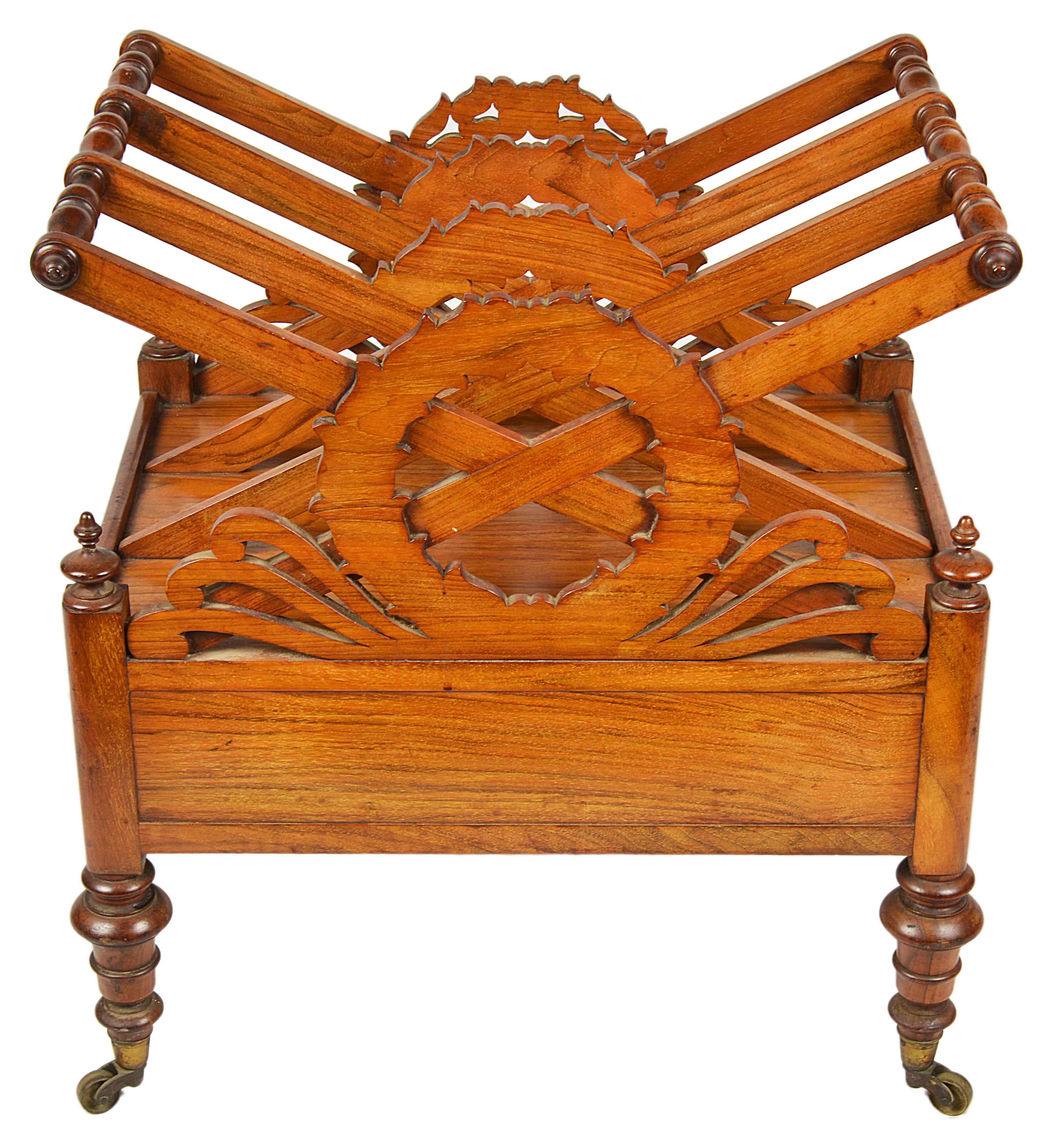 A stylish Regency canterbury, with three divisions united by turned spinials, and a carved laurel wreath to the front, which is silhouetted on the divisions behind. The wreath flanked with scroll carvings and turned finials to all four corners above