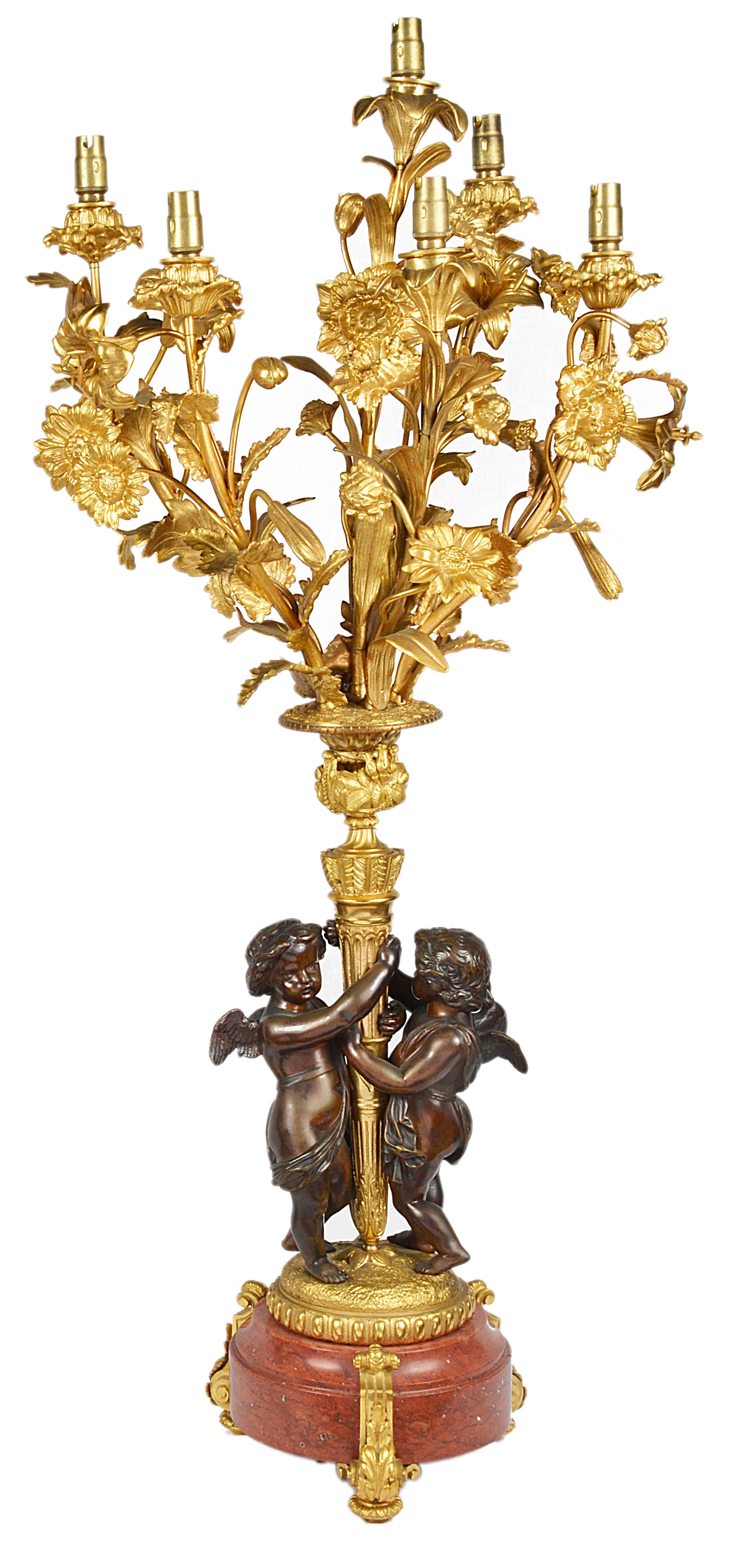A very impressive pair of French 19th century Louis XVI style candelabra. Each having bronze cherubs supporting the gilded ormolu six branch floral candelabra, raised on rouge marble bases.