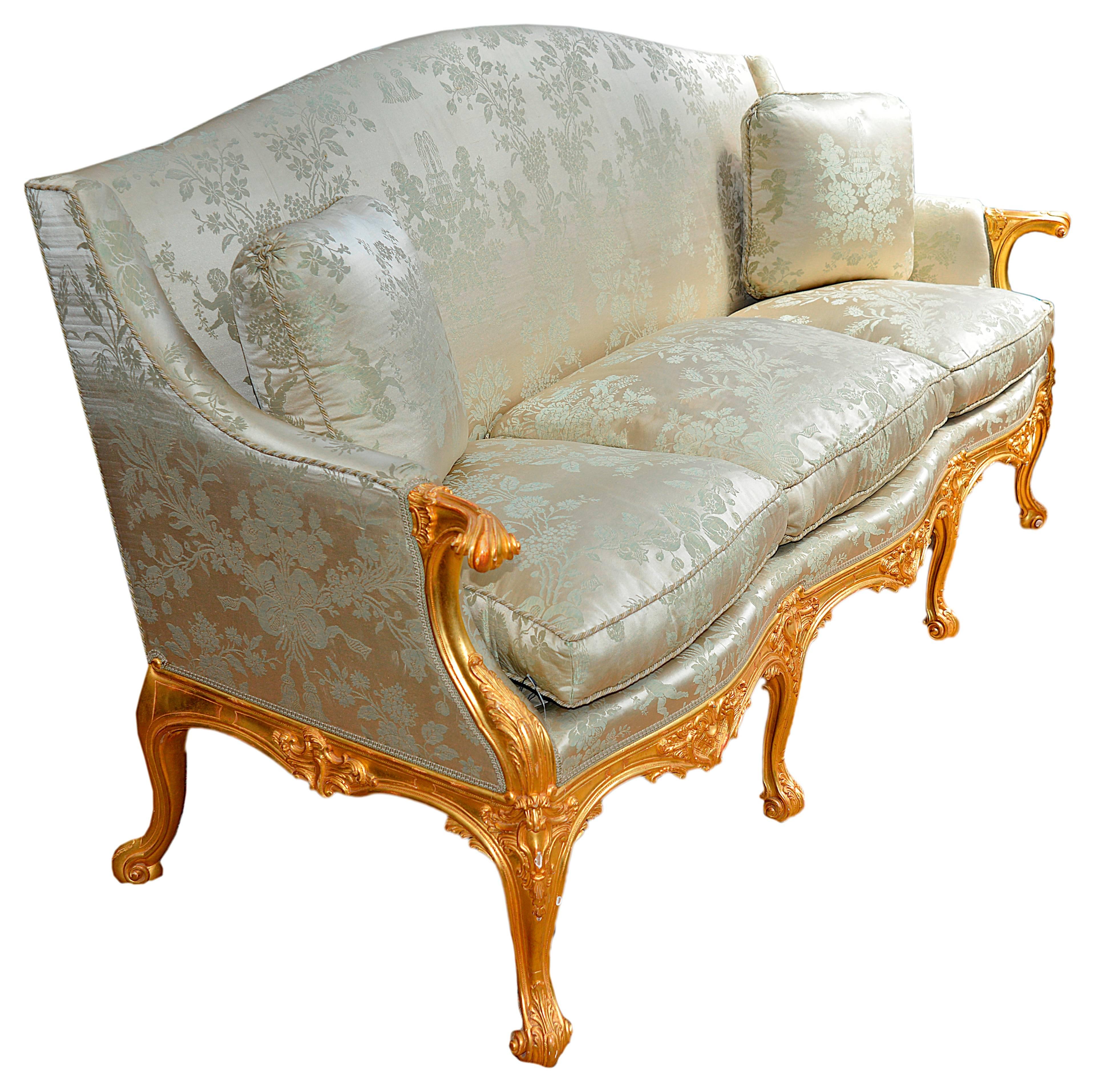 An impressive pair of French giltwood Louis XVI style sofas, each having stuff over upholstery with feather cushions. The frames with scrolling foliate decoration, raised on four carved cabriole legs to the front and four to the back.