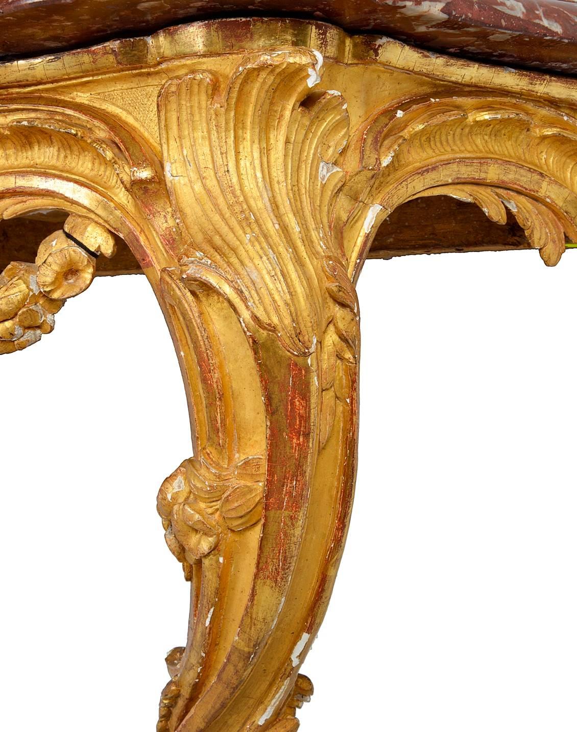 A good quality 18th century French gilded console table with the original rouge marble top. The frieze having a carved giltwood shell, floral swags and raised on cabriole legs united by a stretcher beneath with further flowers and shell decoration.
