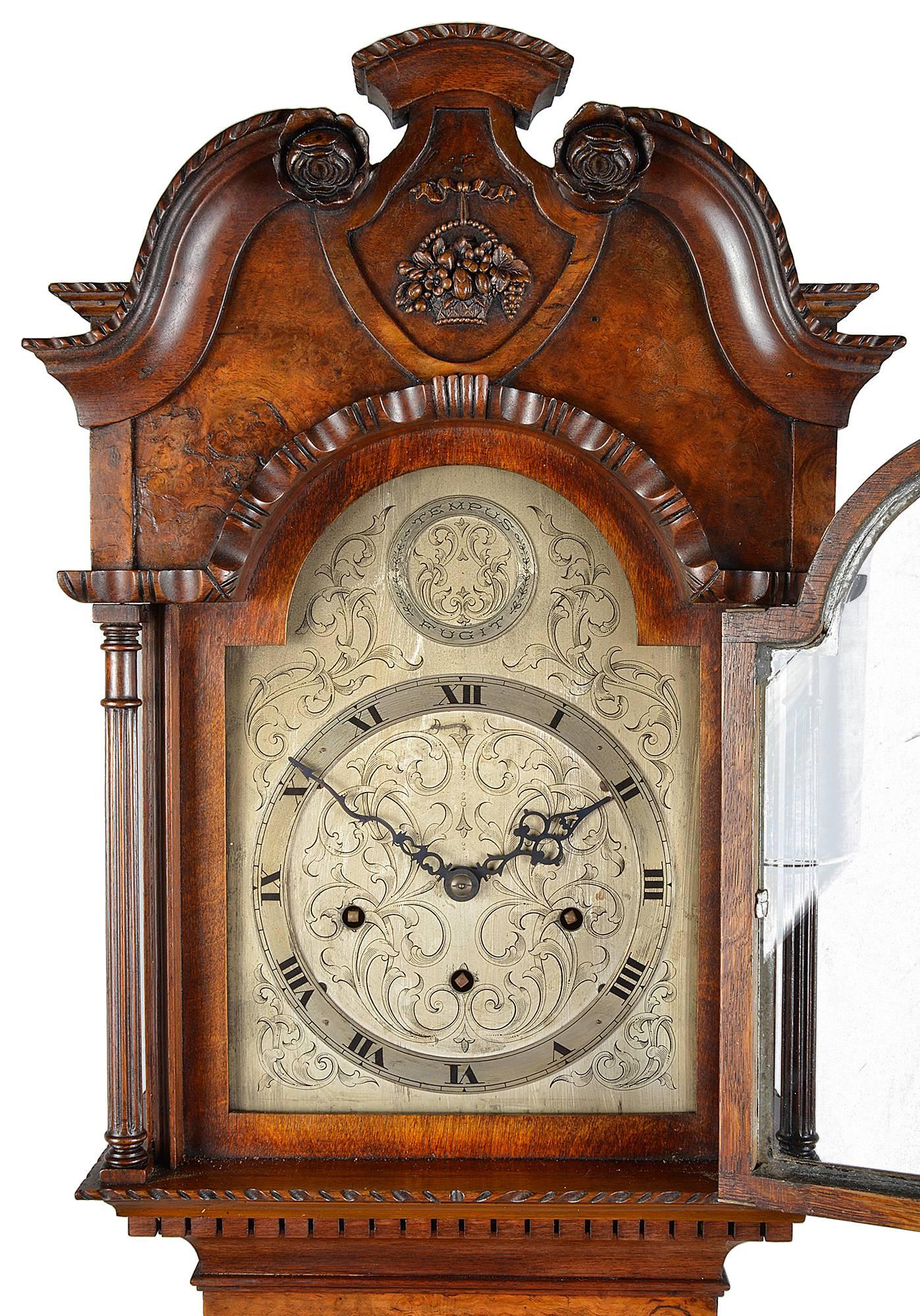 A very good quality Queen Anne style, burr walnut grandmother clock. Having a swan neck pediment, a silvered arch dial clock face, with three train striking movement.