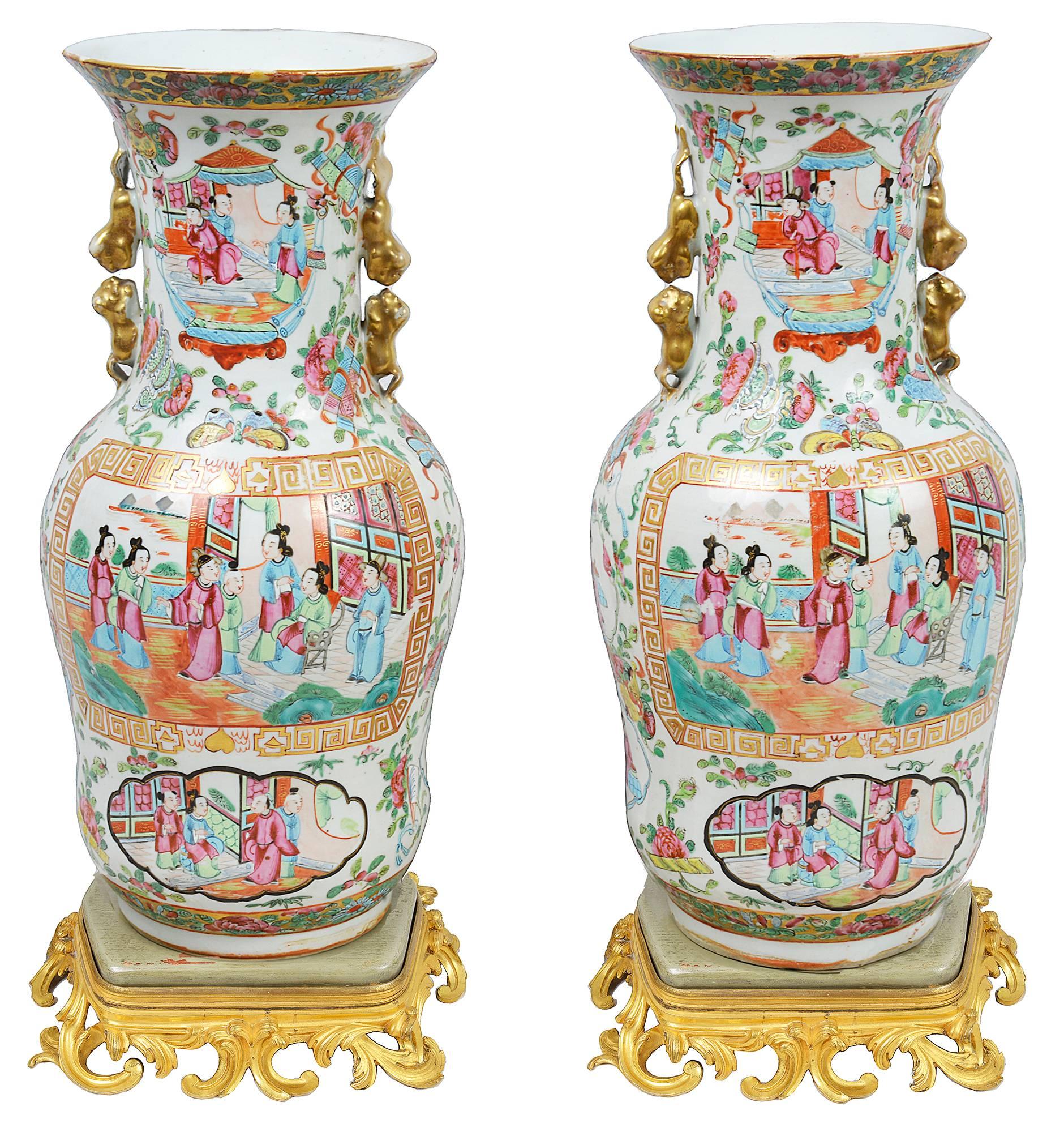 A very good quality pair of Chinese rose medallion Cantonese vases, each depicting classical oriental interior scenes, set in floral surrounds. Set on a pair of French gilded ormolu bases. (Not attached).