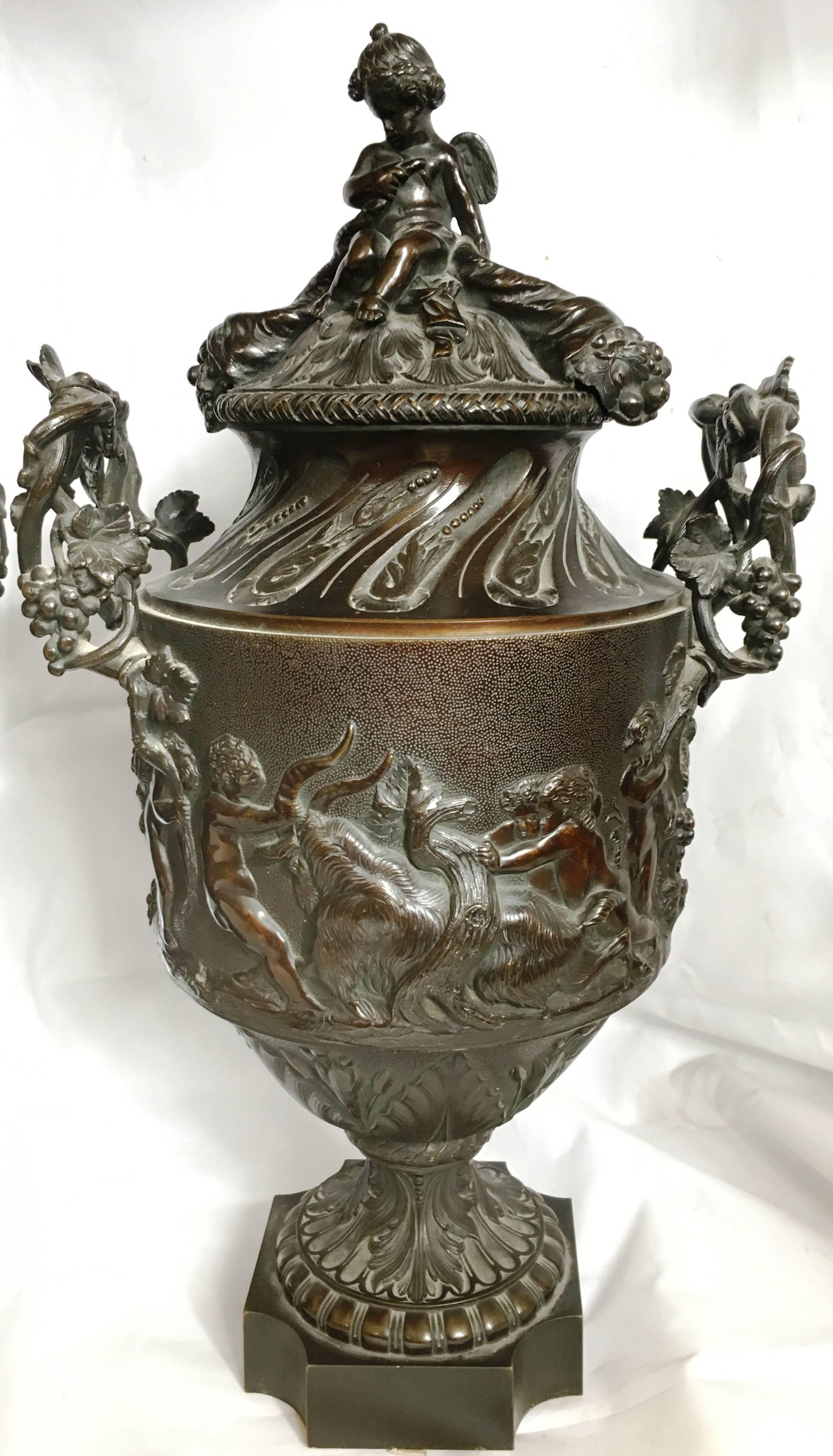 A very impressive pair of 19th century classical bronze urns lidded urns with cherubs on. Entwined grapevine handles and putti playing with grapes and rams.