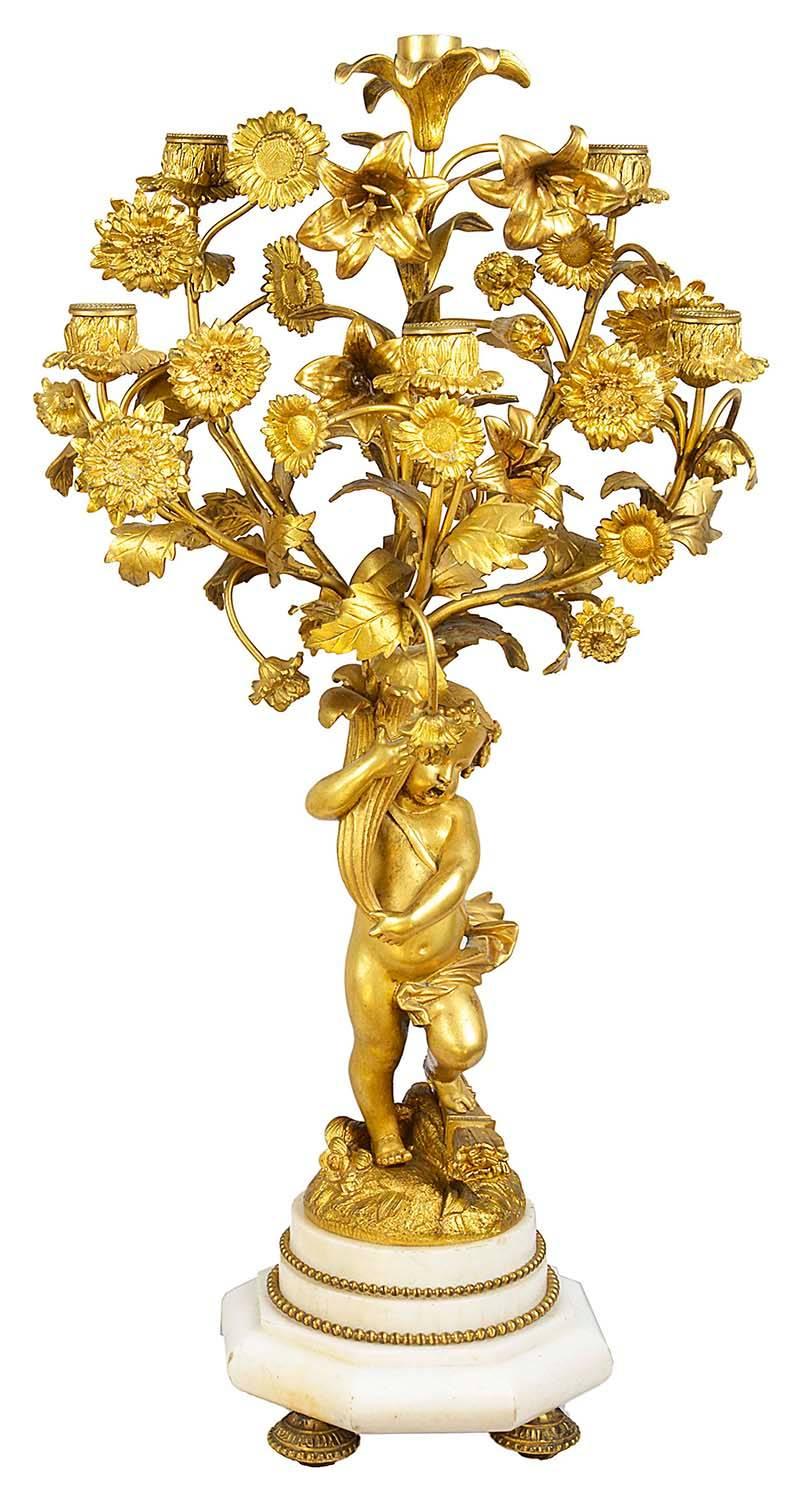 A good quality pair of 19th century French gilded ormolu and white marble candelabra, in the Louis XVI style. Each having eight-branch ormolu candle sconces amongst flowers and leaves, held by apposing putti and mounted on white marble bases.
