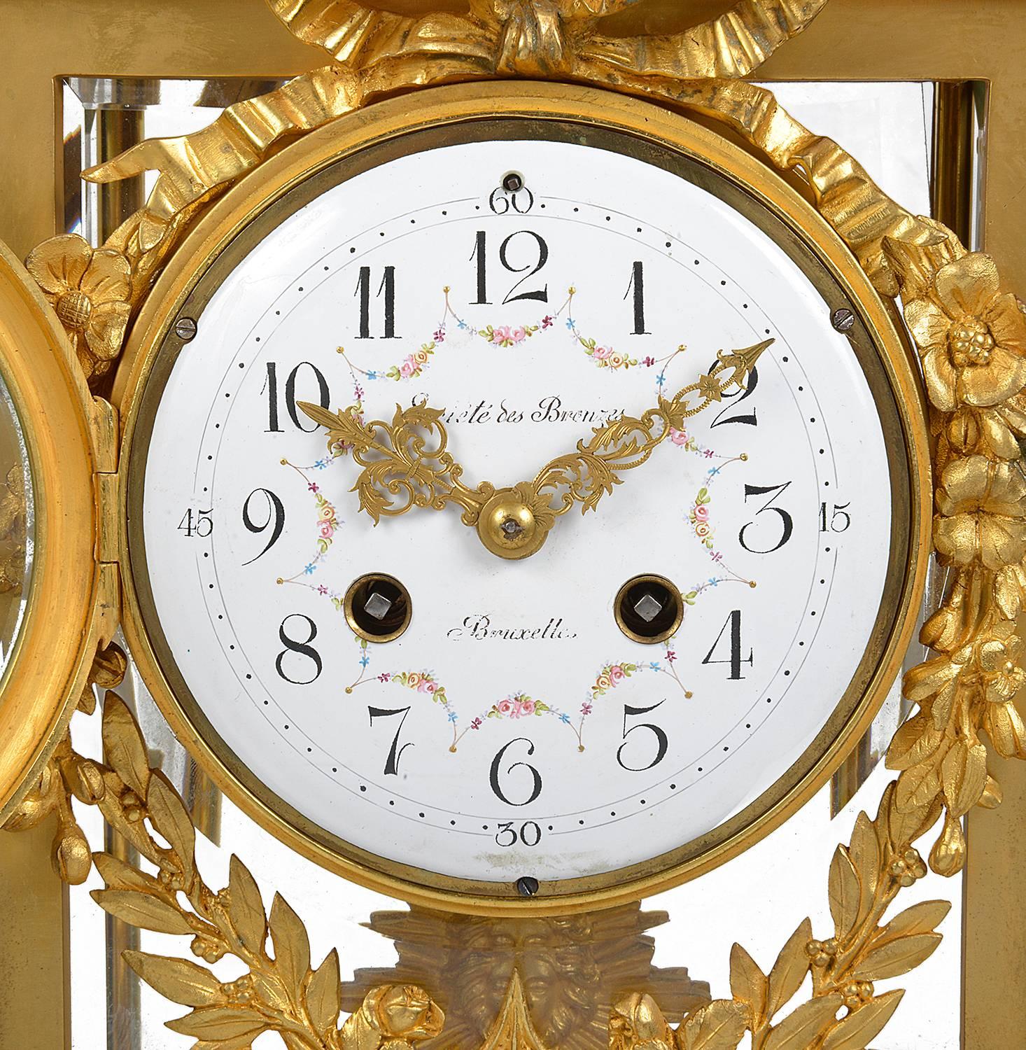 A good quality 19th century French gilded, Louis XVI style ormolu mantel clock. Having a gilded wreath and arrow sheath above a white marble top, ormolu four glass case, with a white enamel clock face, an eight day striking movement, flower and