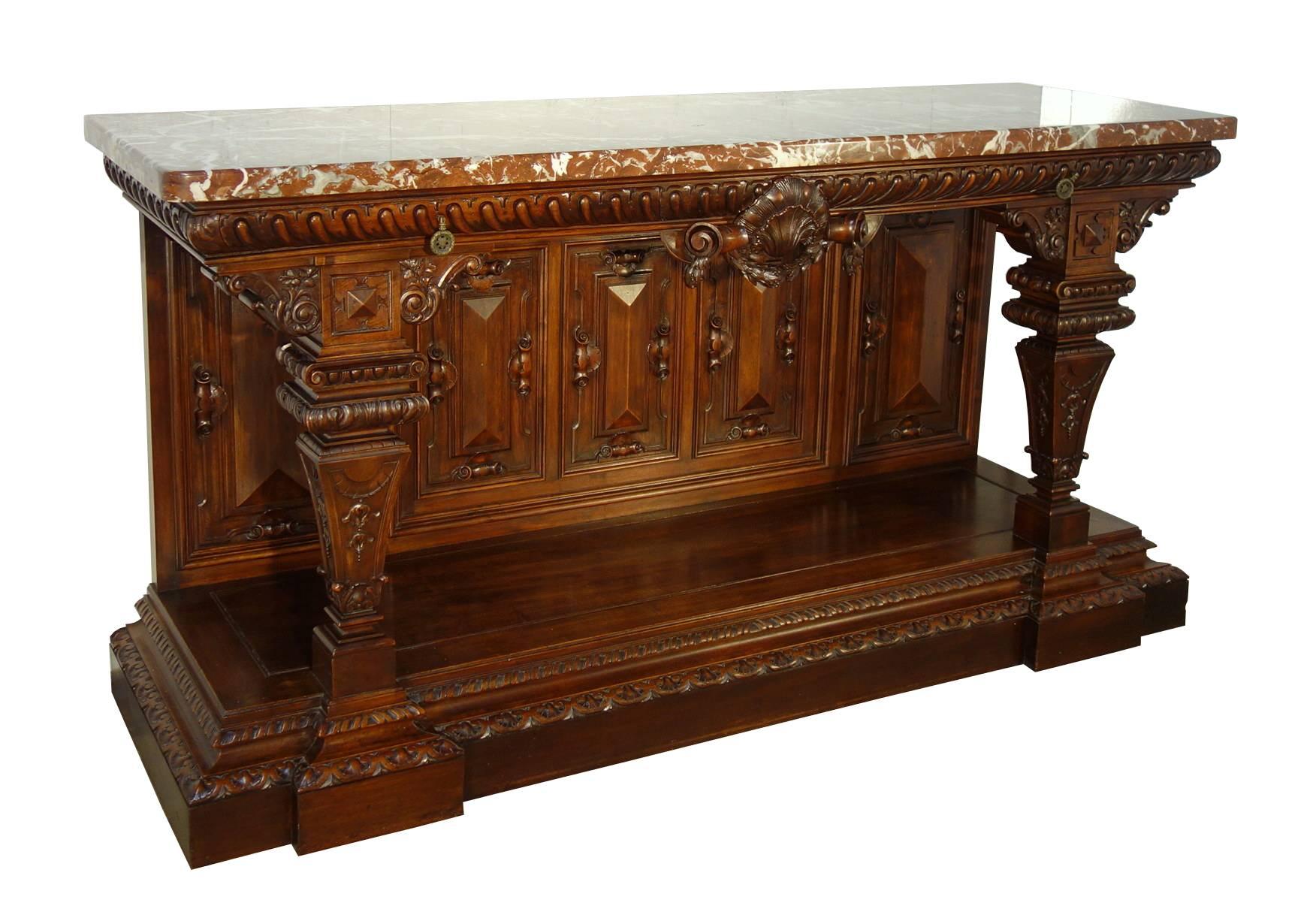 Incredible large Tuscan hand-carved solid walnut console table, pure Renaissance style with fine patina.  Marble top in thick Breccia Rosa, two drawers in the top band hand-carved with baccellature, a typical Renaissance motif.  Column square