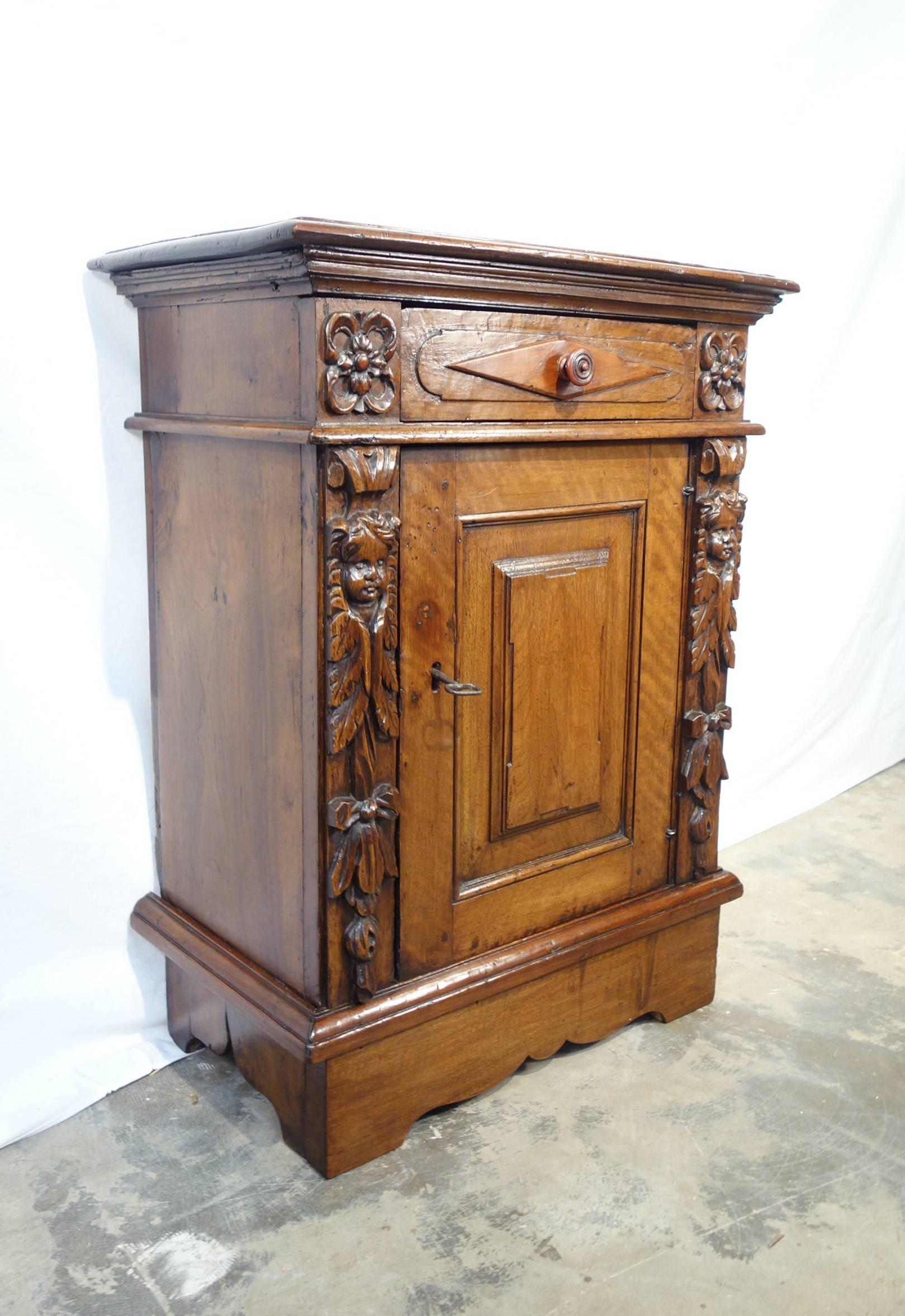 19th century Renaissance style nightstand made of warm color solid walnut with one-drawer and one locking door, with key.
Wonderful hand-carved cherubs faces with triumph of leaves on the front sides. Interesting solid walnut single slab back