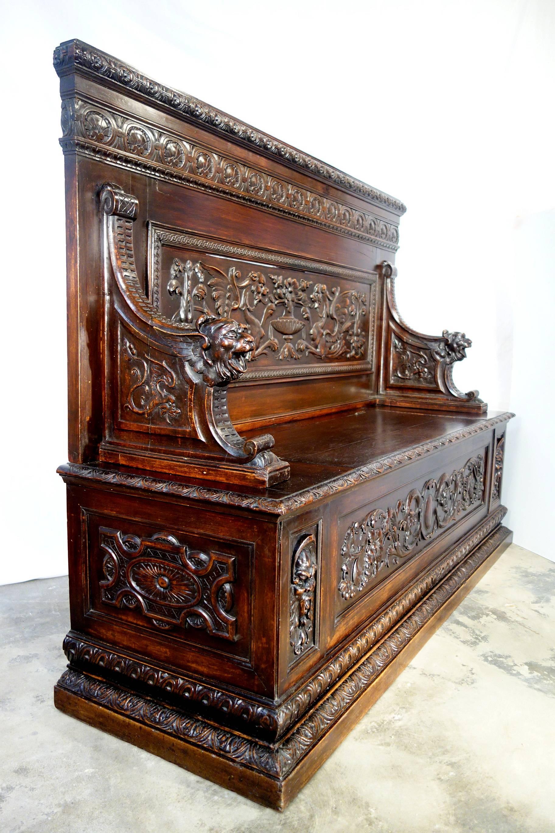 Impressive 19th century bench of solid walnut with heavily hand-carved Renaissance motif of dragons, lion heads, chalise & vines. The seat lid opens to reveal storage.

Measures: 65