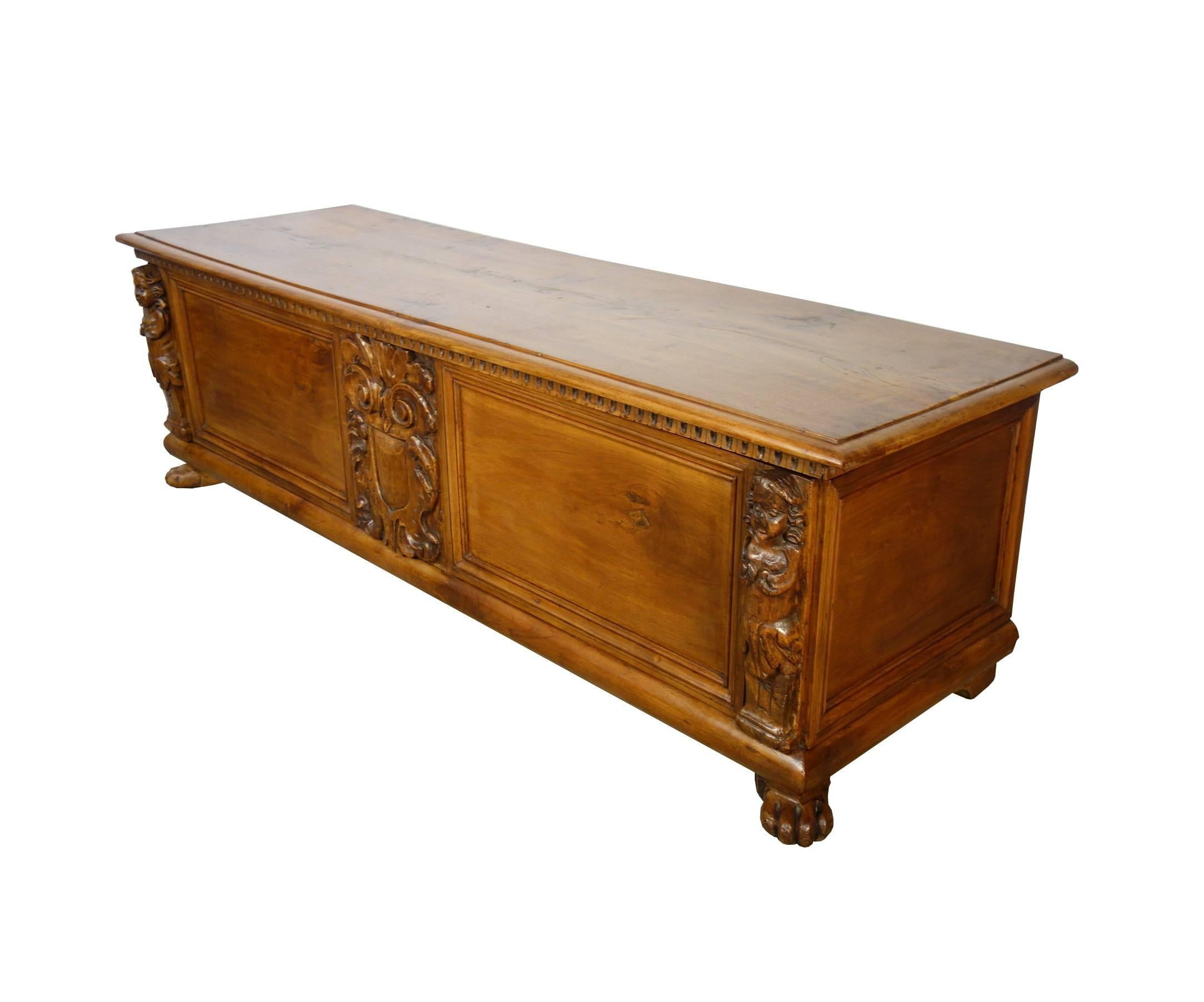 Impressive 17th century Tuscan solid walnut long trunk with hand-carved caryatids and family crest. Simple lines and elegant. Light walnut color.

Measures: 67.5