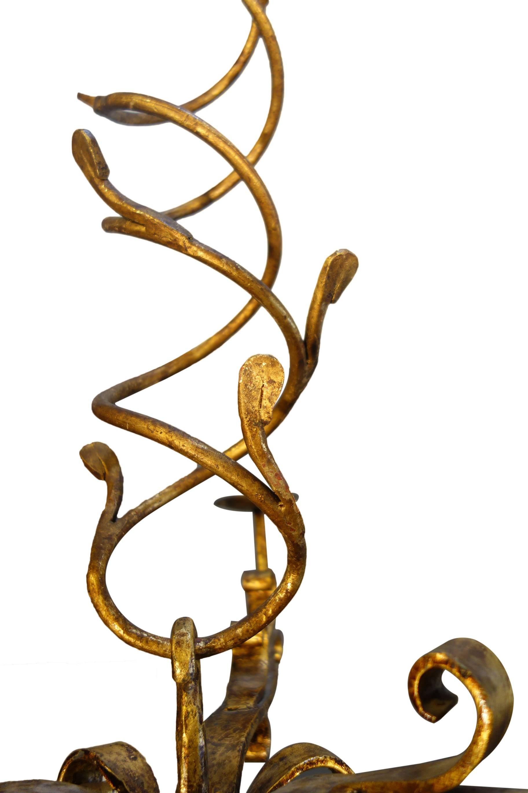 Italian Mid-Century Nouveau chandelier, hand-forged wrought iron and gold gilded; a descending gold stylized plant spiral "vine" supporting three lights.

Available as a similar fixture with four lights on a coupled straight arm, for