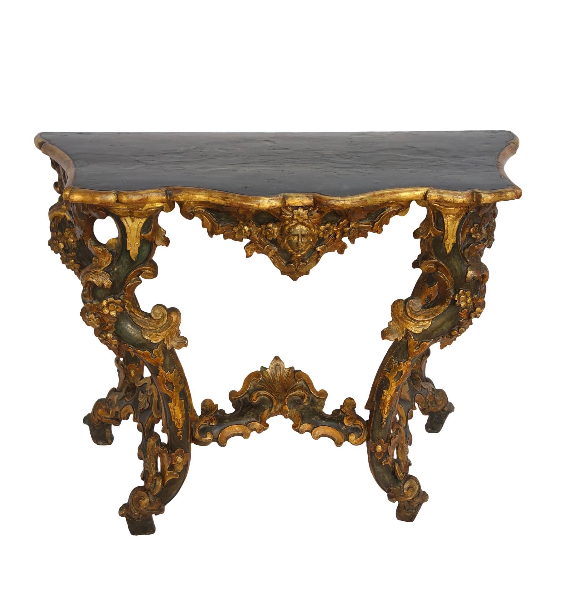 Unique pair of 18th Century painted console tables.
Dark green blue painted with gold gilt details on faces and on the details of the fruit triumph decoration around the legs structure and beautiful cross bar motifs. The whole surmounted by
