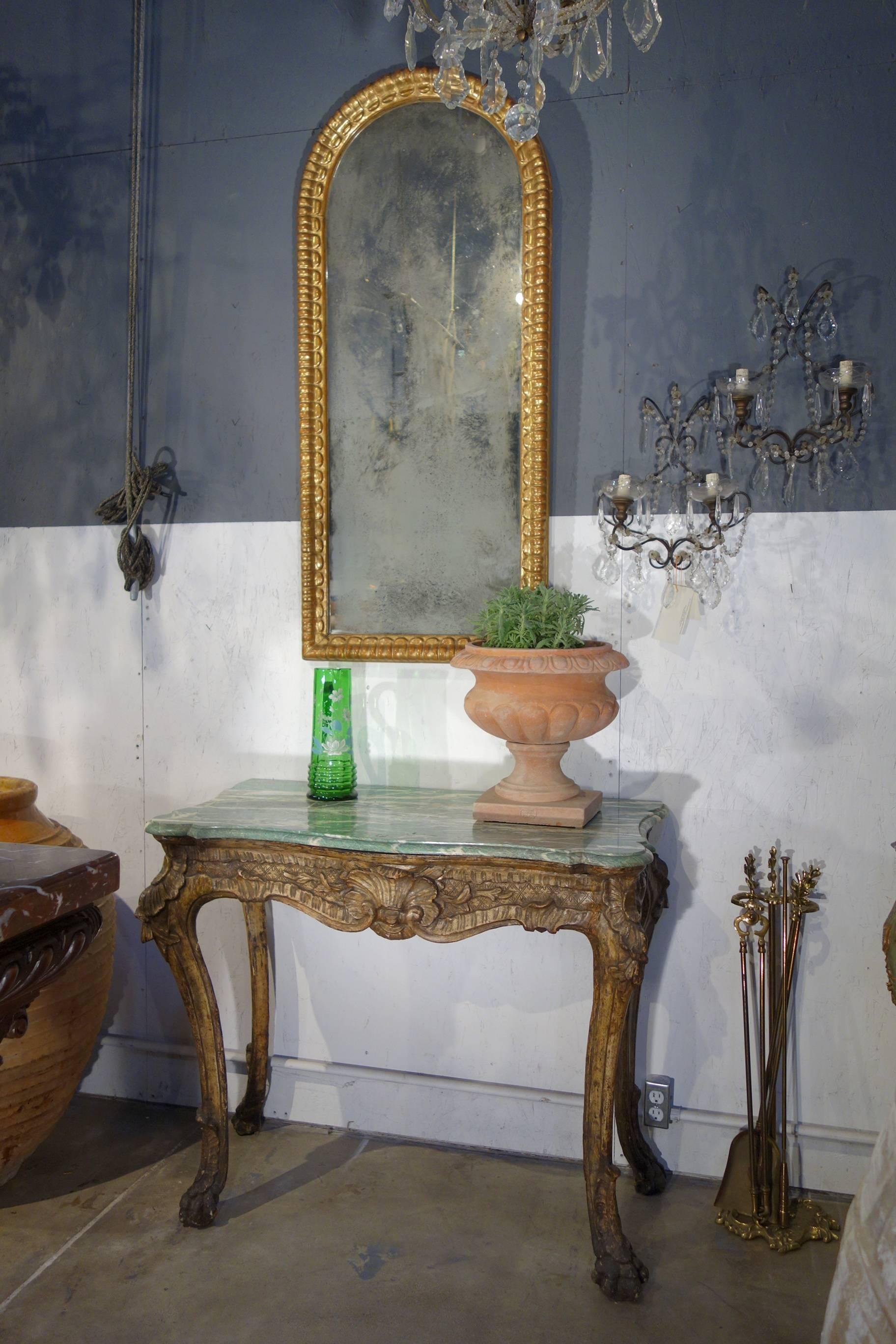 Miroir vertical ovale italien ancien du début du XIXe siècle de style baroque, doré à l'or.
Ravissant miroir ovale en forme de niche doré avec détails sculptés à la main.  procédé de feuille d'or «olo ».  Miroir au mercure d'origine avec une bonne