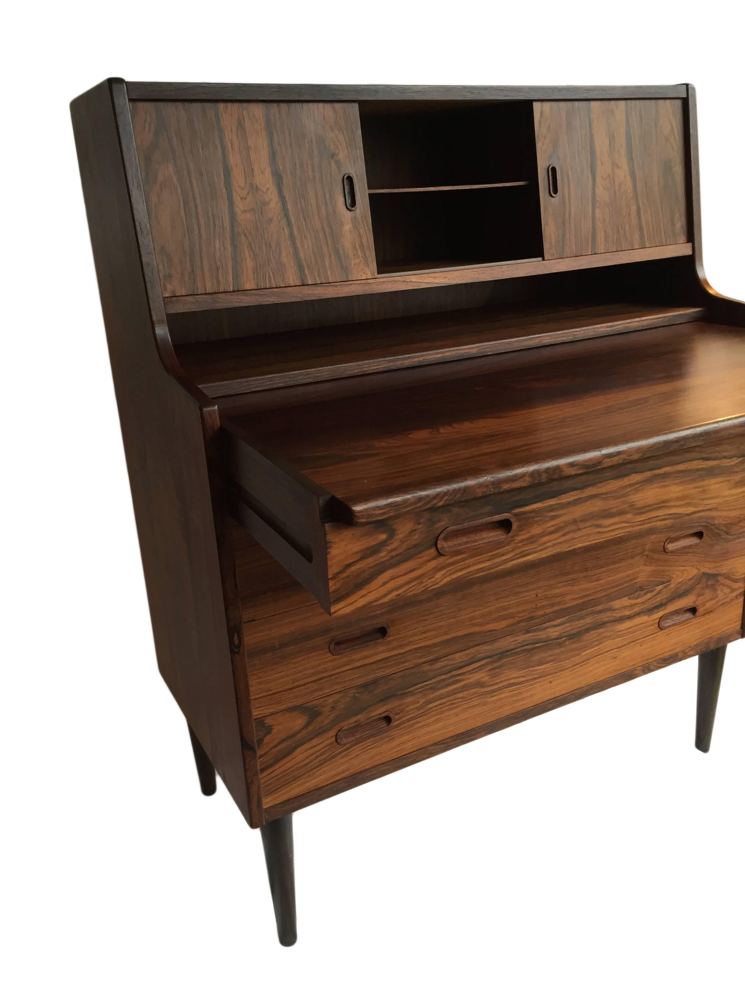 A very fine Brazilian rosewood bureau produced in Denmark circa 1960.
Excellent grain. Superb condition.
Pullout desk surface with interior compartments and flip out mirror.
