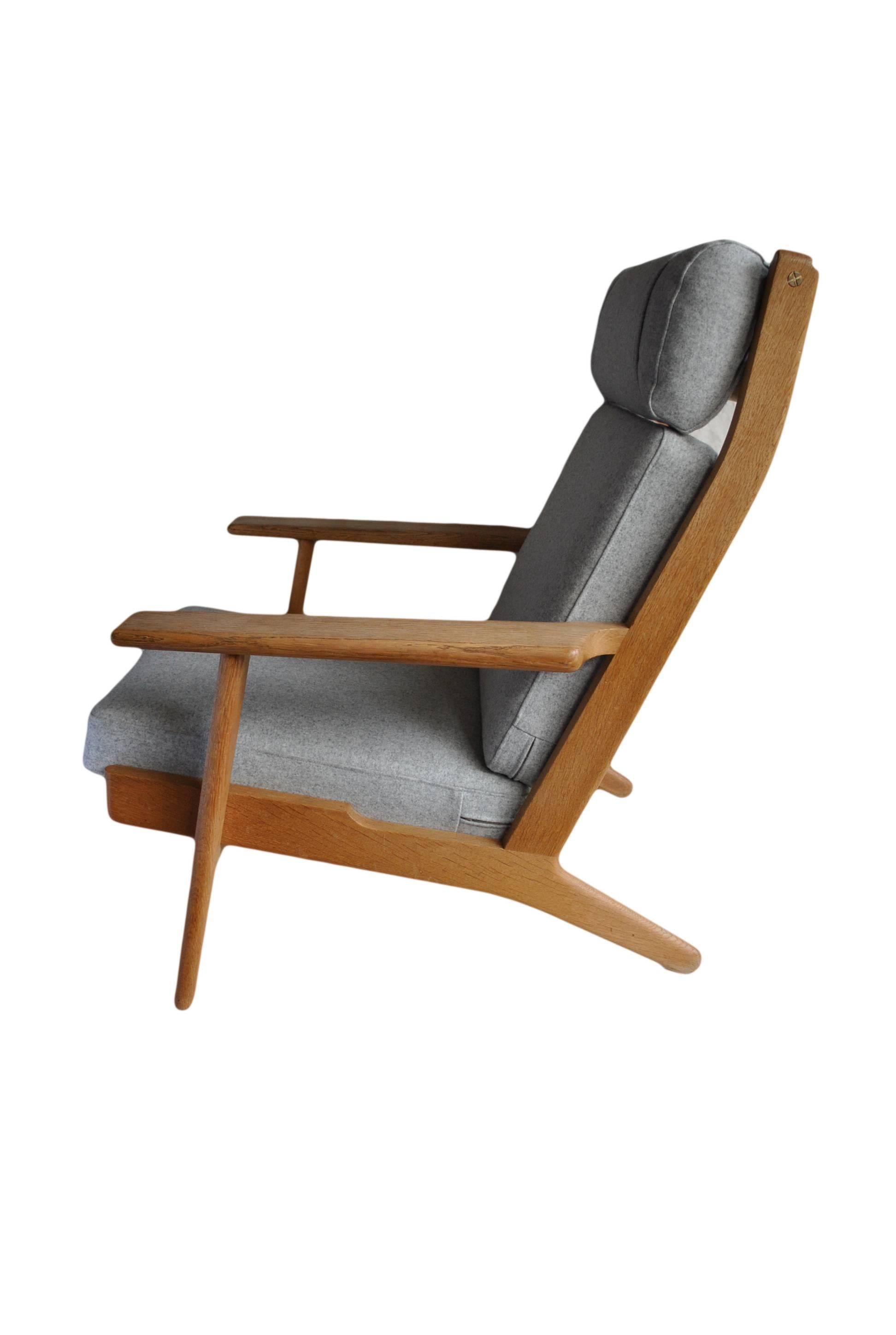 An original 1950s GETAMA GE290 high back lounge chair by Hans J Wegner. Freshly reupholstered metal sprung cushions in grey felt. Repolished solid light European oak frame - in superb condition throughout. Makers/designers marks still intact to