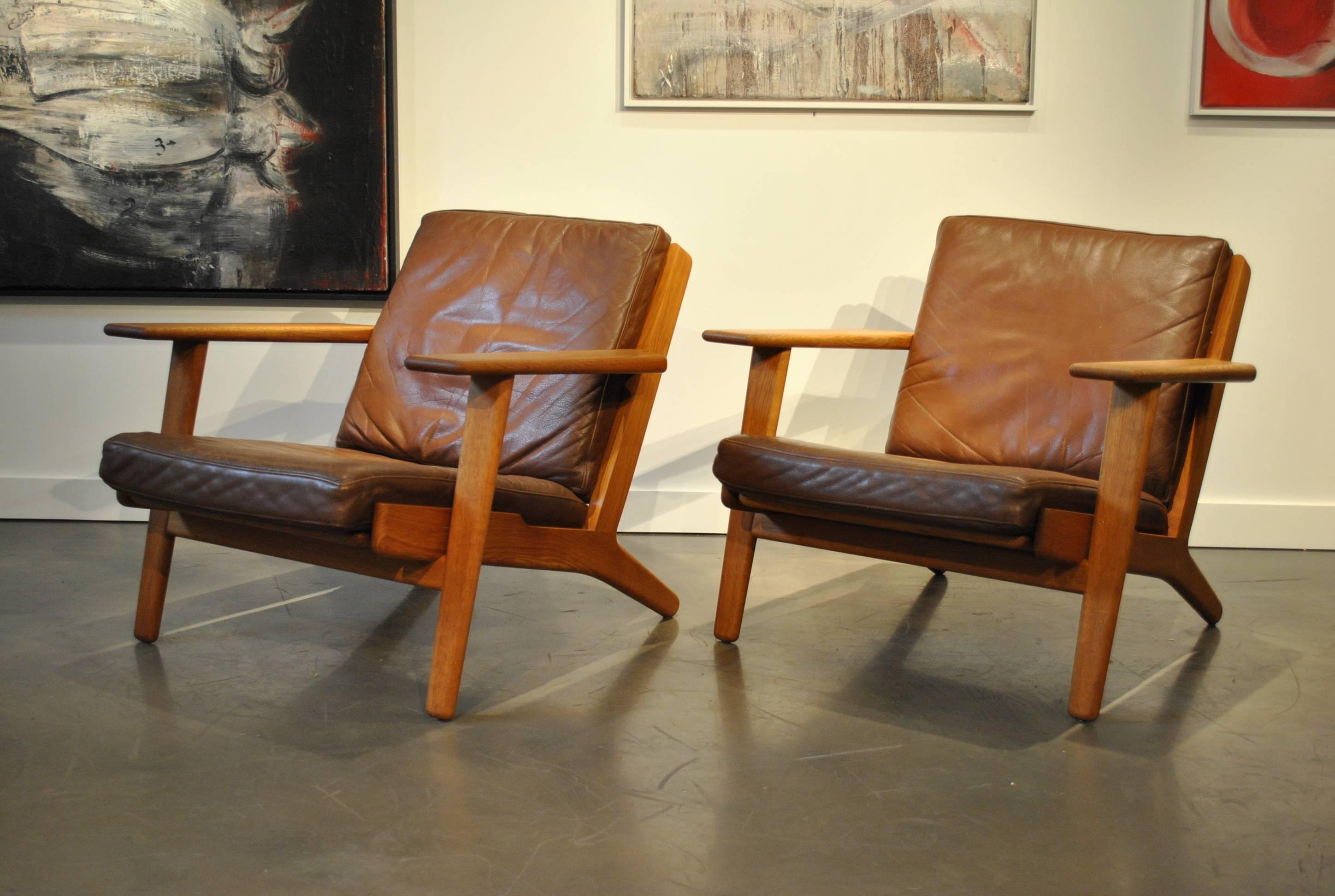 Early light European oak version of Hans J Wegners ge290 design for GETAMA. Produced in Denmark, circa 1955. A Classic and timeless design. Sympathetically refurbished - Repolished frames with patinated light/mid brown leather upholstery. Original