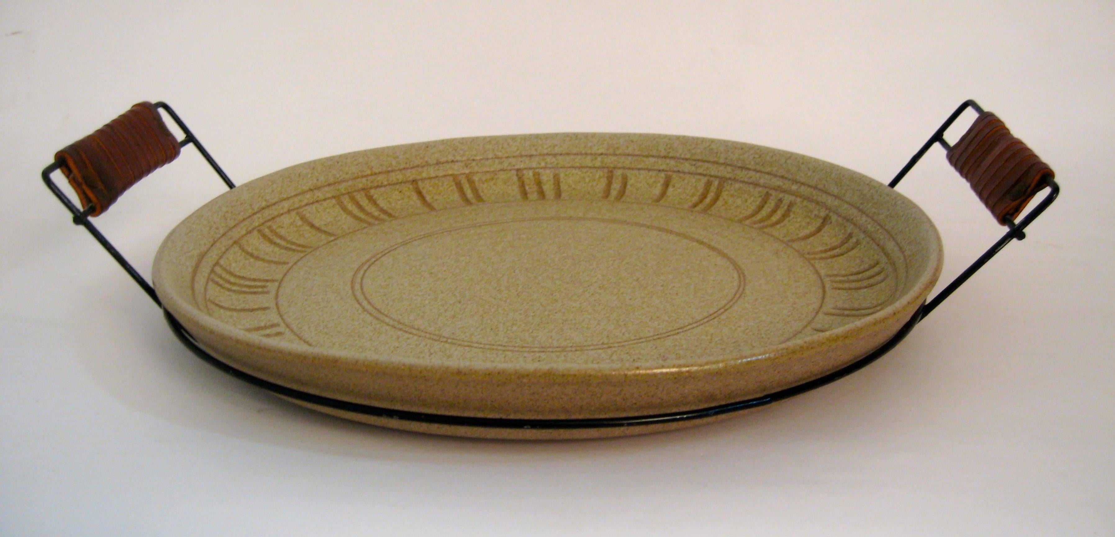 Wonderful and rare form signed Gordon Martz serving platter centrepiece. Large matte glazed pottery dish with a metal wire and leather wrapped handle caddy. Incised line motif decorated edge in a speckled tan glaze. Excellent, original condition.