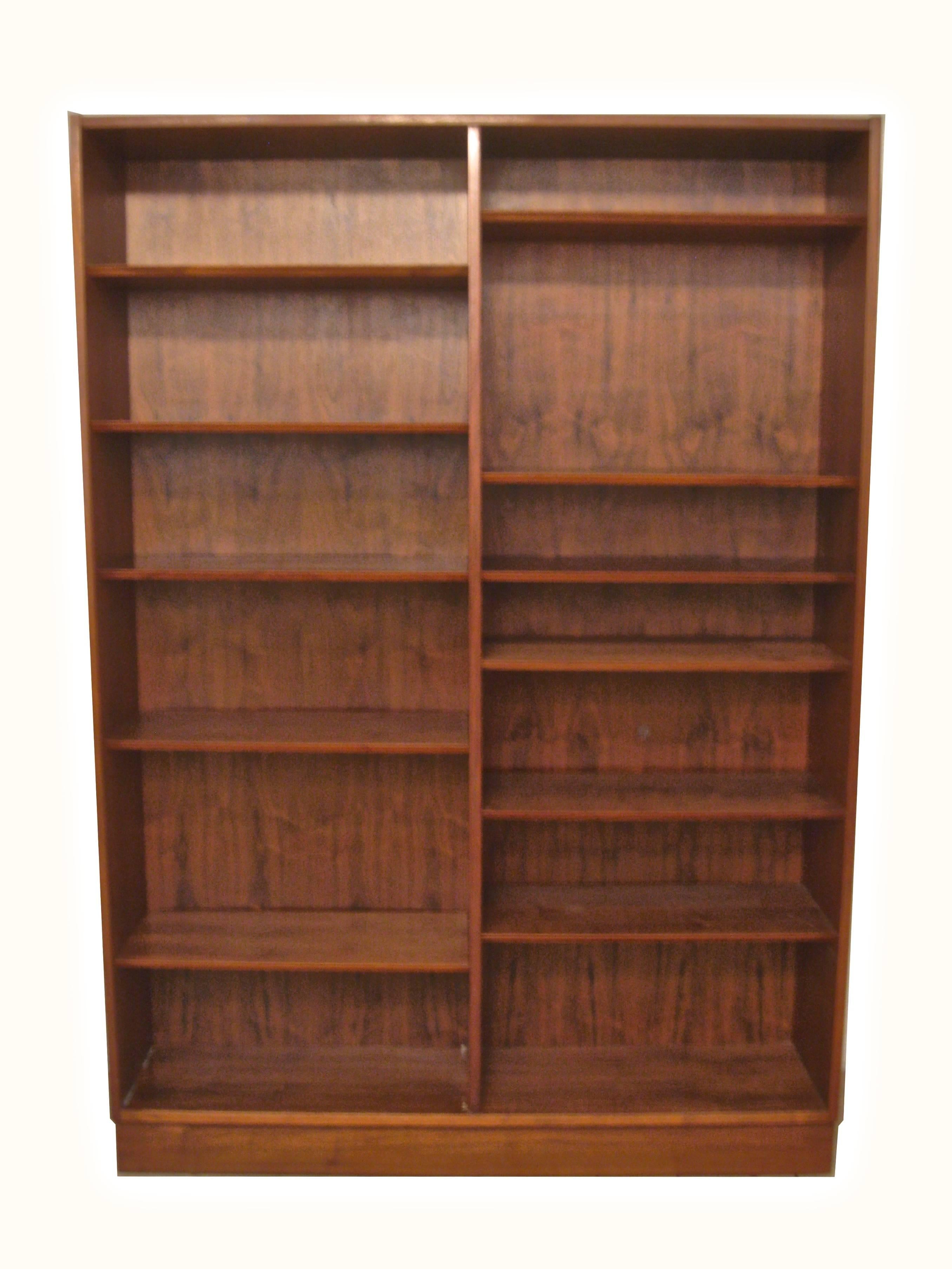 Made of wonderfully figured teak veneers. Solid wood construction. Two fixed shelves surrounded by ten adjustable shelves. The shelves are adjusted with hidden metal wire pins. One deep shelf for electronic devices with two holes for snaking wires.