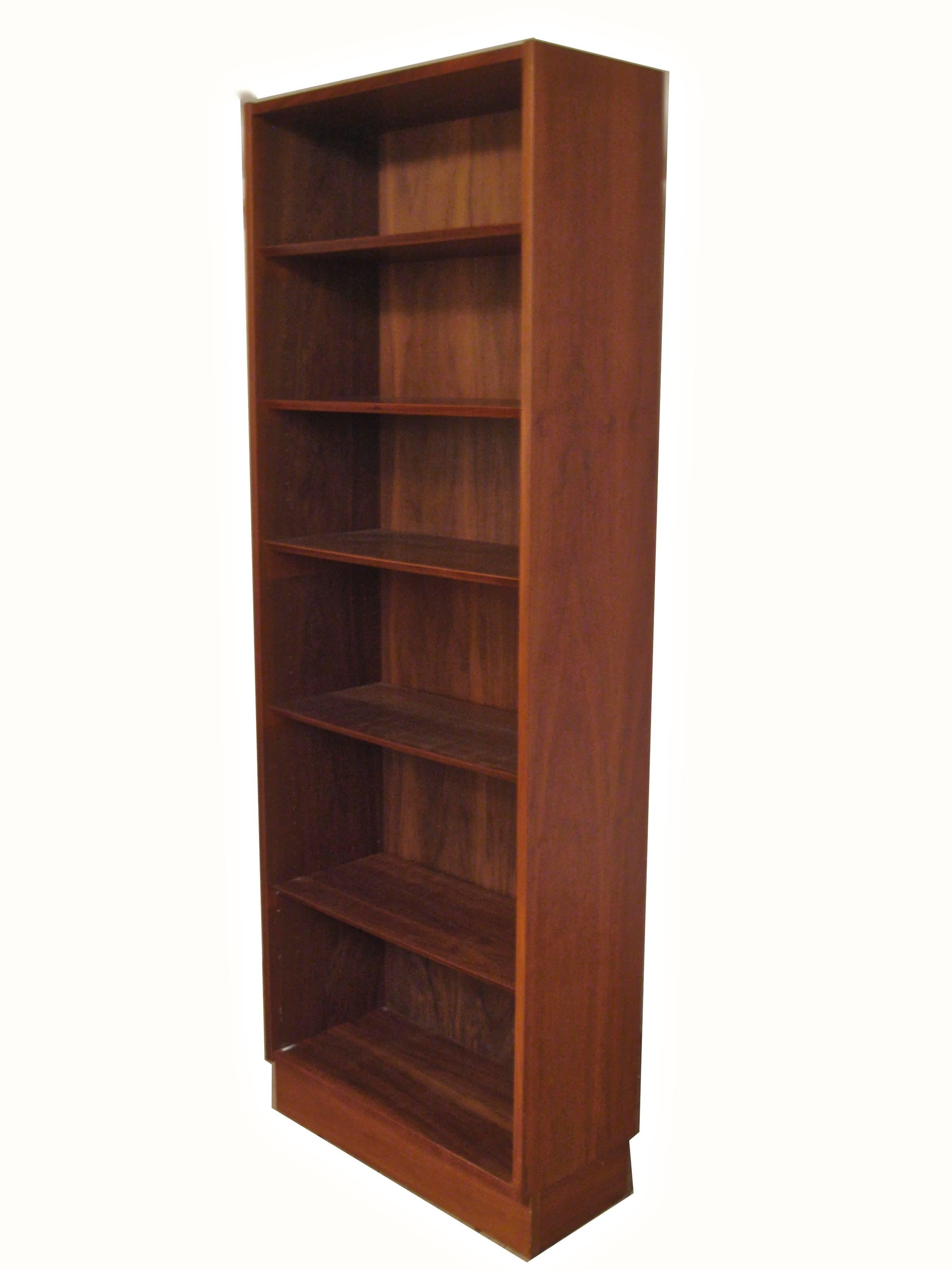 Made of wonderfully figured teak veneers. Solid wood construction. One fixed shelf surrounded by five adjustable shelves. The shelves are adjusted with hidden metal wire pins. One deep shelf for larger books or devices. Unsigned missing Hundevad/
