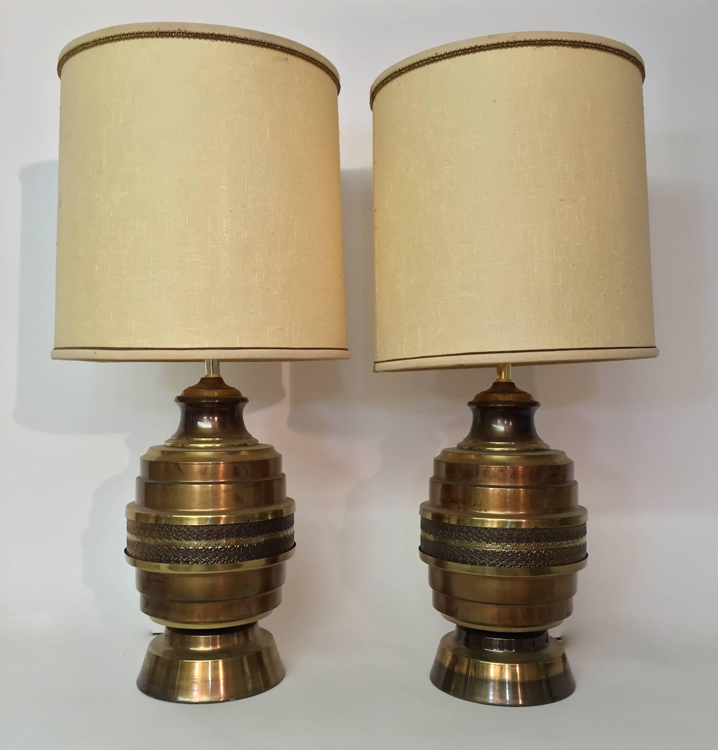 Fine pair of 1960s copper and brass finish lamps. The middle band is decorated in a floral scroll pattern. Large and impressive with a very nice mellow patina.

Shades are not included.