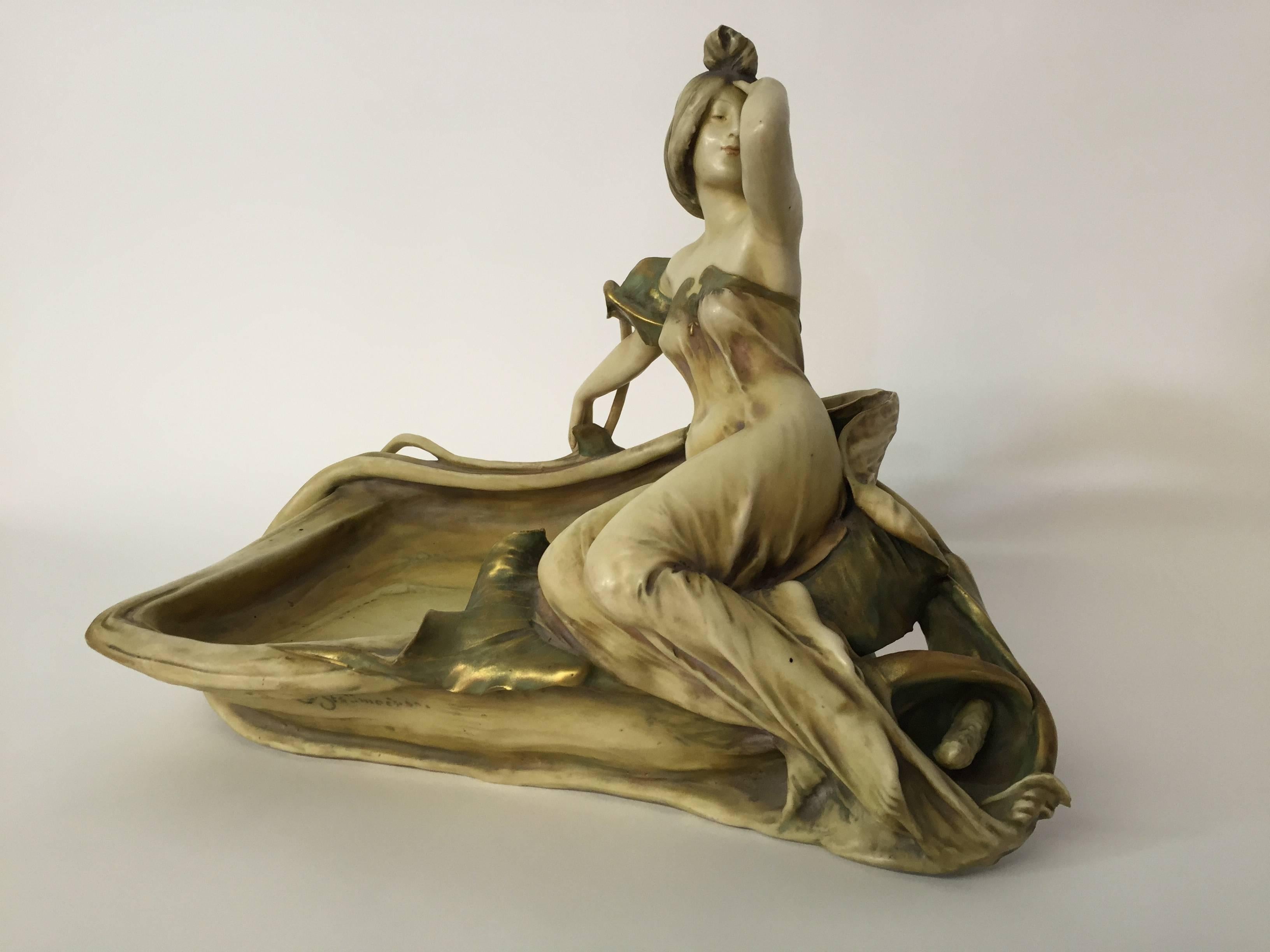 Signed Eduard Stellmacher Art Nouveau pottery centerpiece for Riessner, Stellmacher and Kessel, Turn-Teplitz, Bohemia. Made in Austria, circa 1890-1910. 

Undulating, dramatic and exceptional figure of a reclining lady resting on a lily. Glazed in