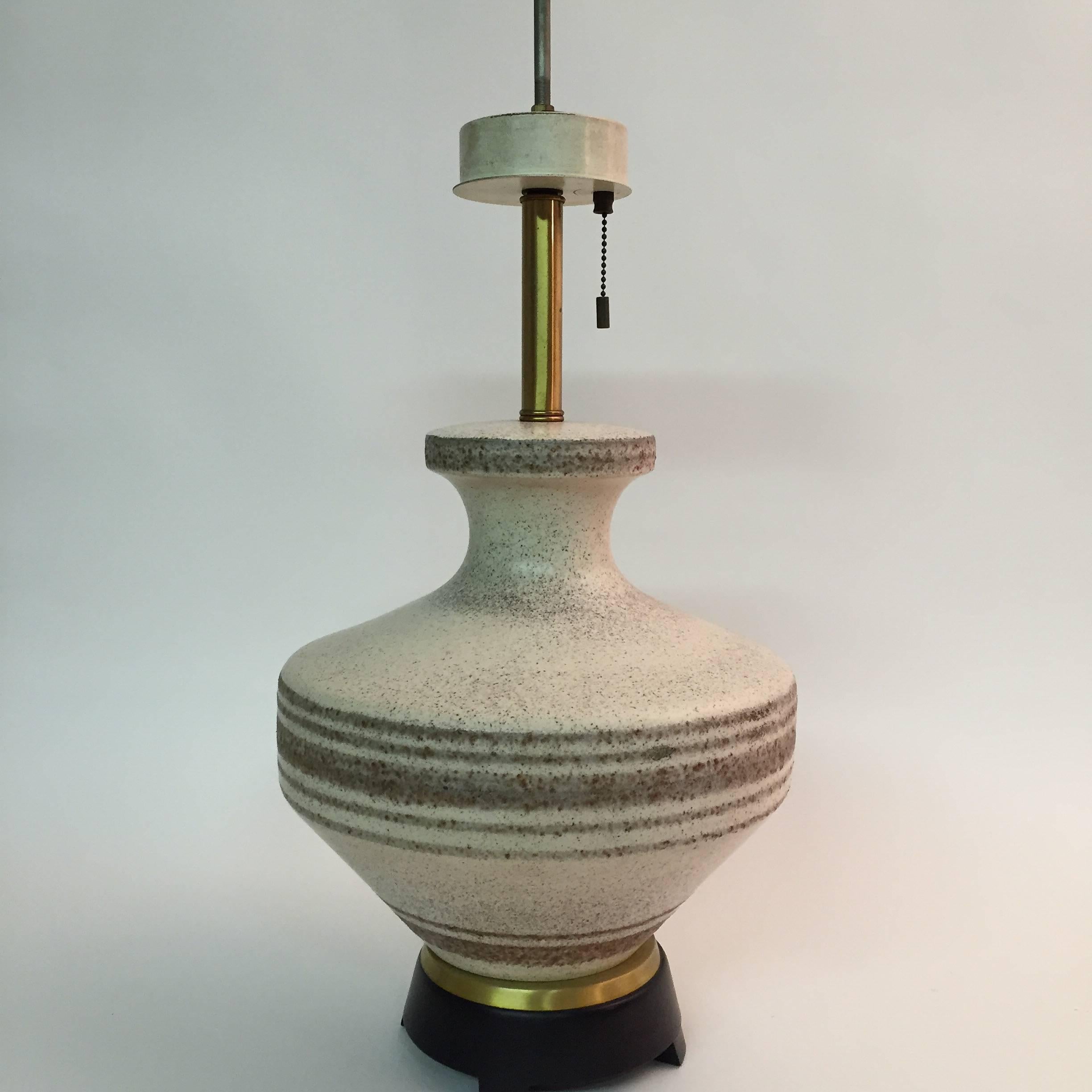 Excellent matte glazed pottery lamp designed by Gerald Thurston for Lightolier. Speckled glaze and hoop decoration. Black matte with brass accent base. Unsigned. The ceramic base measures approximately 12