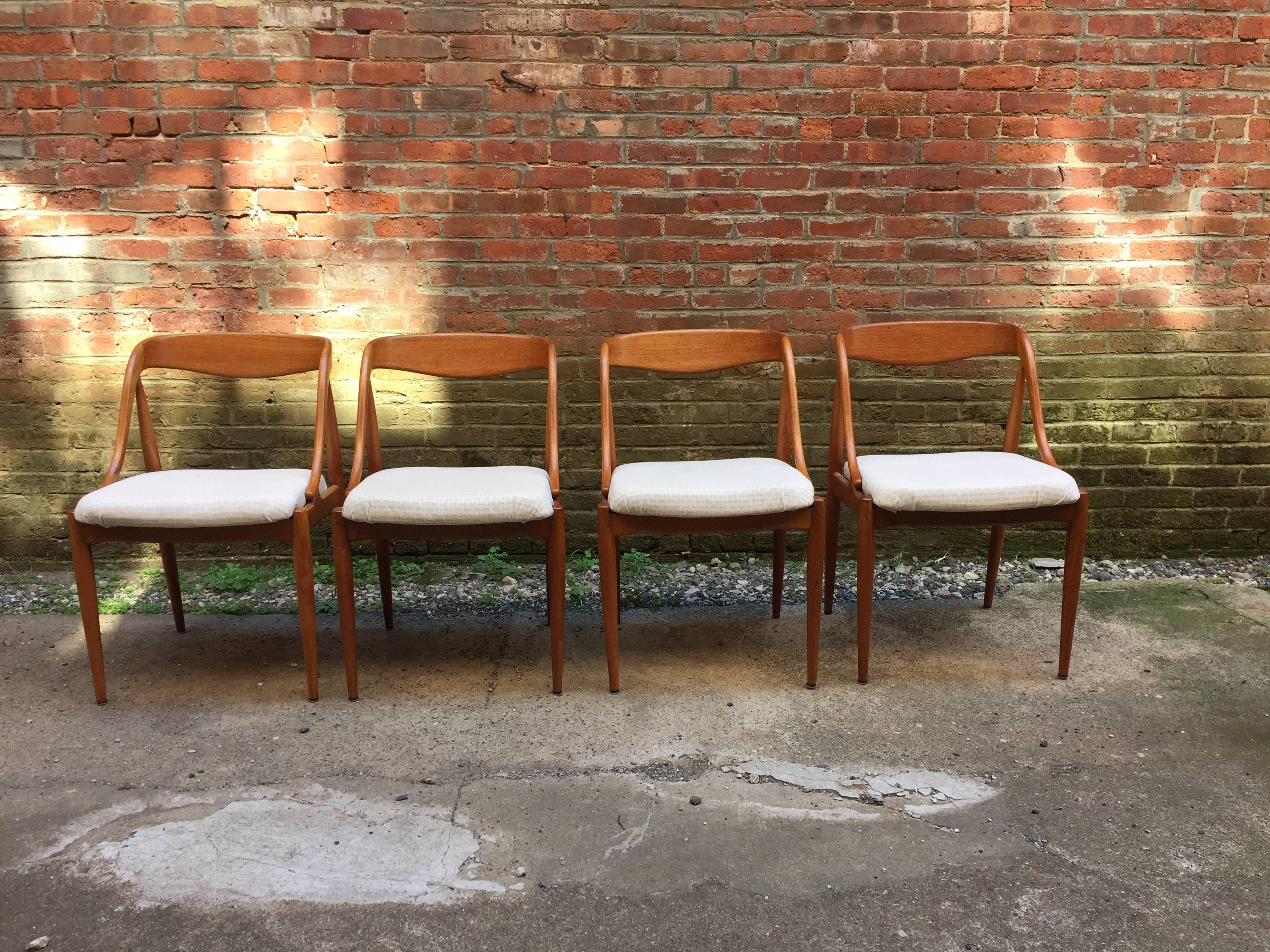 Set of four curvaceous teak dining chairs designed by Johannes Andersen for Moreddi. Covered in a neutral interlace pattern fabric. Fully signed on the bottom of each chair with Danish control stamp.