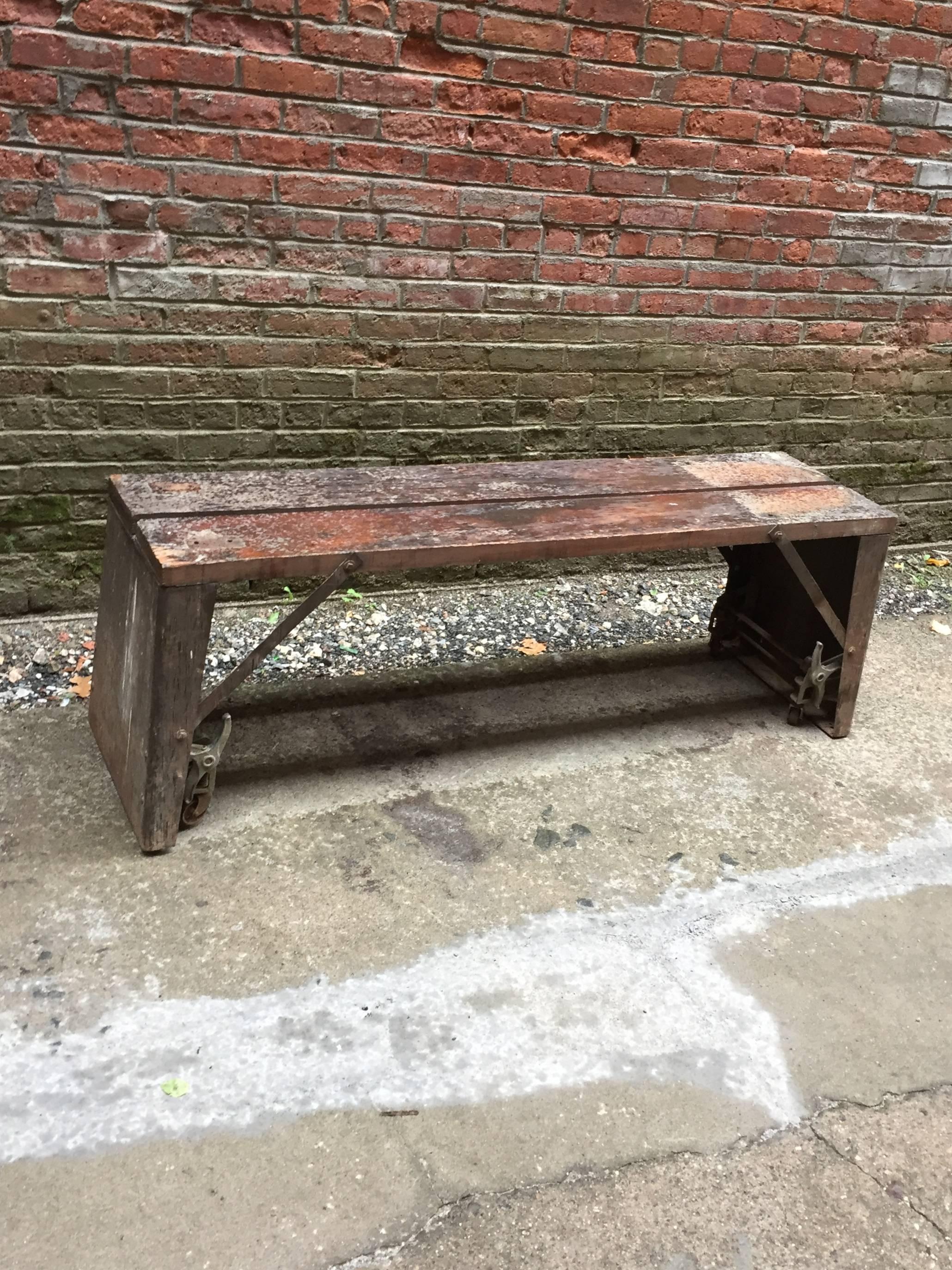 Excellent entry way or mud room bench. Originally, there was a lathe attached to the bench, but it has long been removed. The wheels lock down for easy rolling and unlock once it is in place. Distressed two board wood seat with flared, reinforced