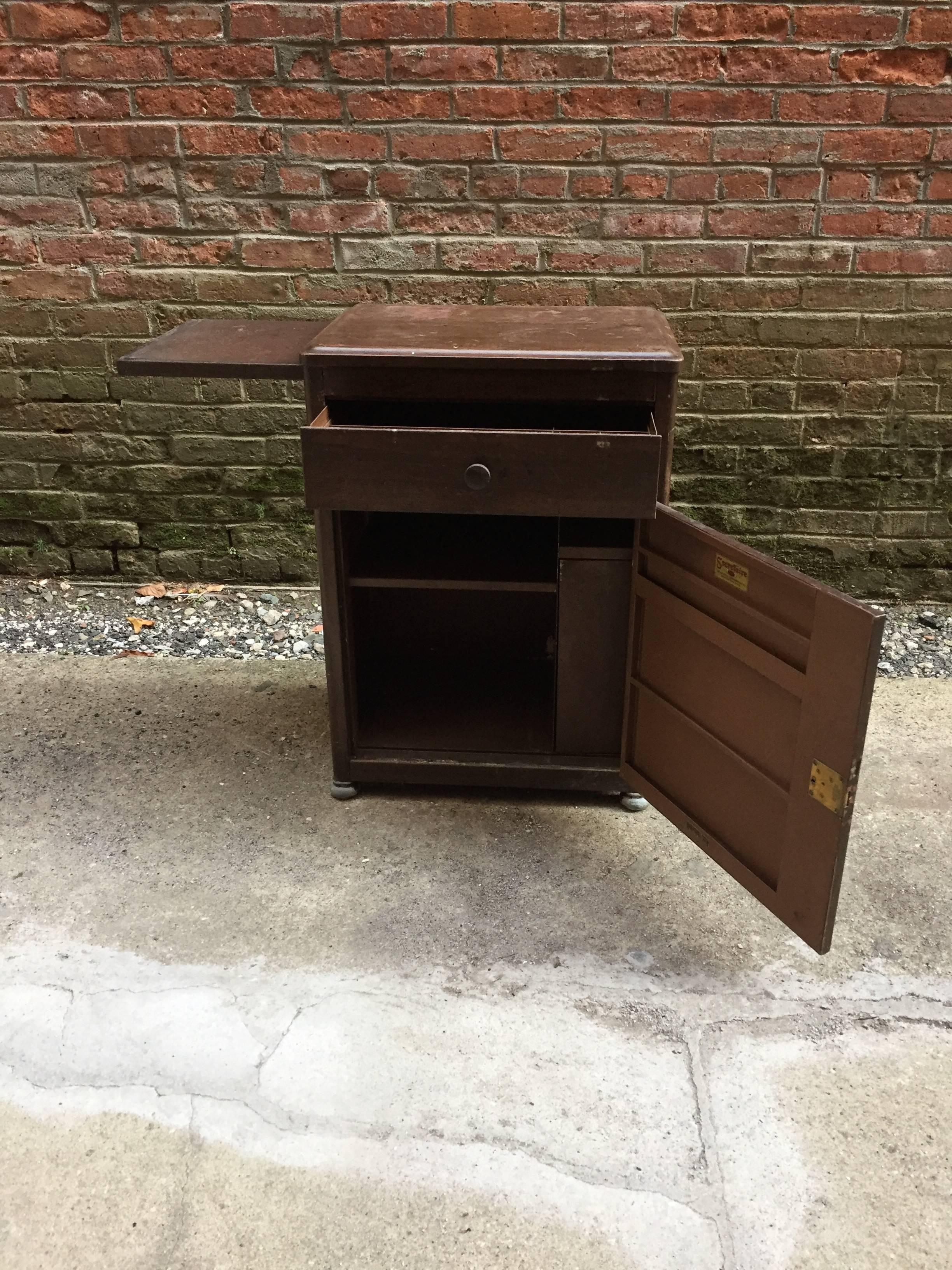 Spectacular metal fireproof cabinet by The General Fireproofing Co., Youngstown, Ohio, circa 1920-1930. The cabinet features a side pull out surface and great space for storage. Wood grain finish exterior over steel. Makes a great end table or