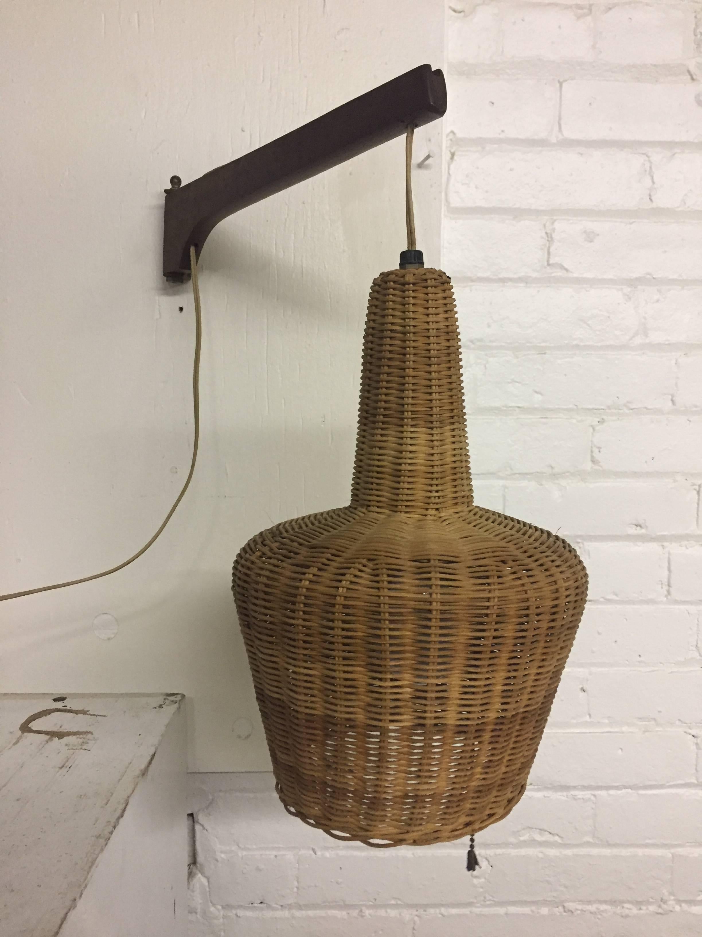 Finely woven wicker hanging shade with a solid teak/walnut swing arm. Original wiring. Pull chain. Probably Danish in origin, circa 1950-1960. Very good, original condition. Unsigned.

Shade measures 8" diameter x 13" high. 18" deep