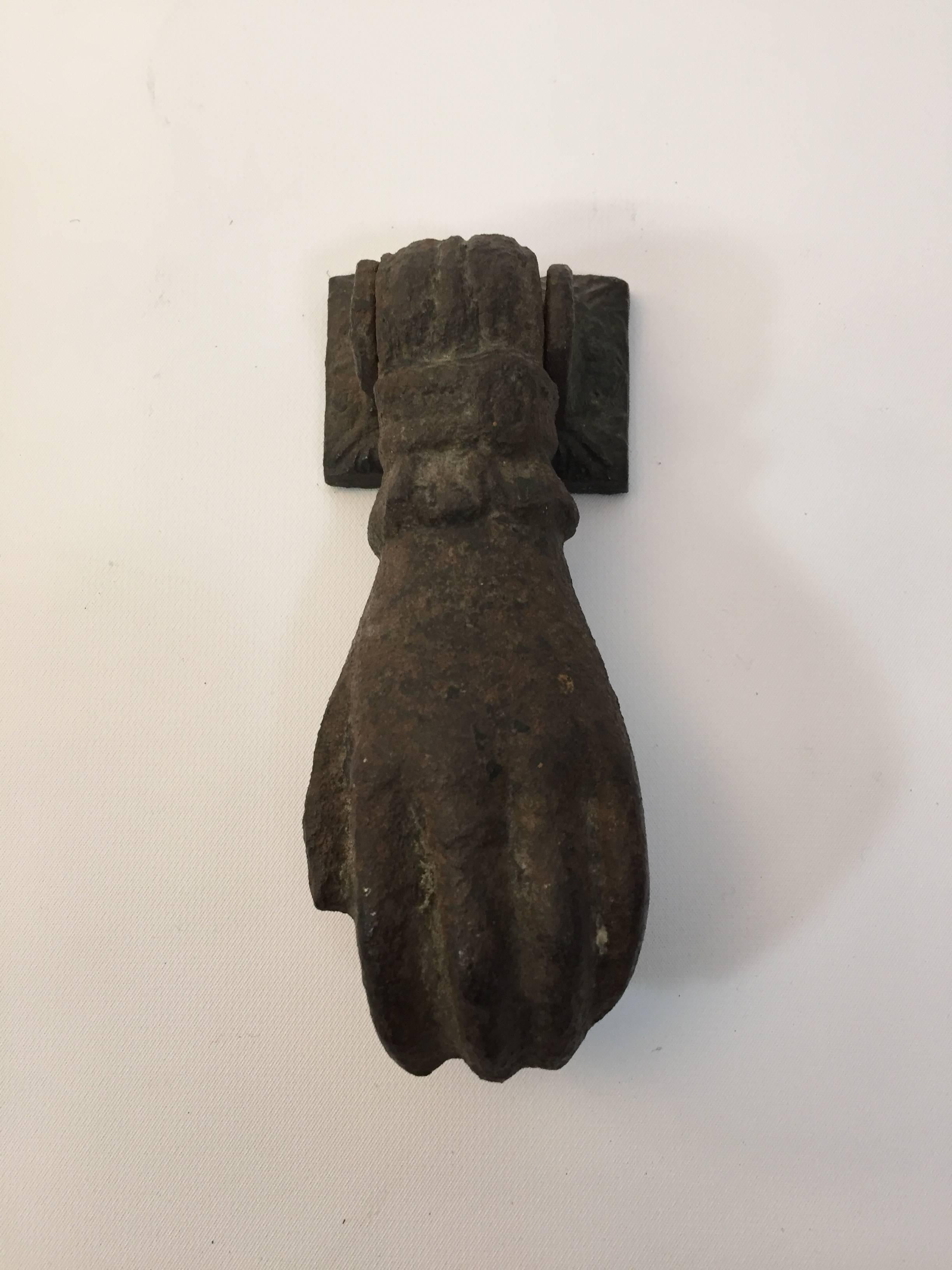 Cast iron figural hand door knocker. The hand holds a small sphere that should come in in contact with a backplate to make a noise, circa 1880-1890.