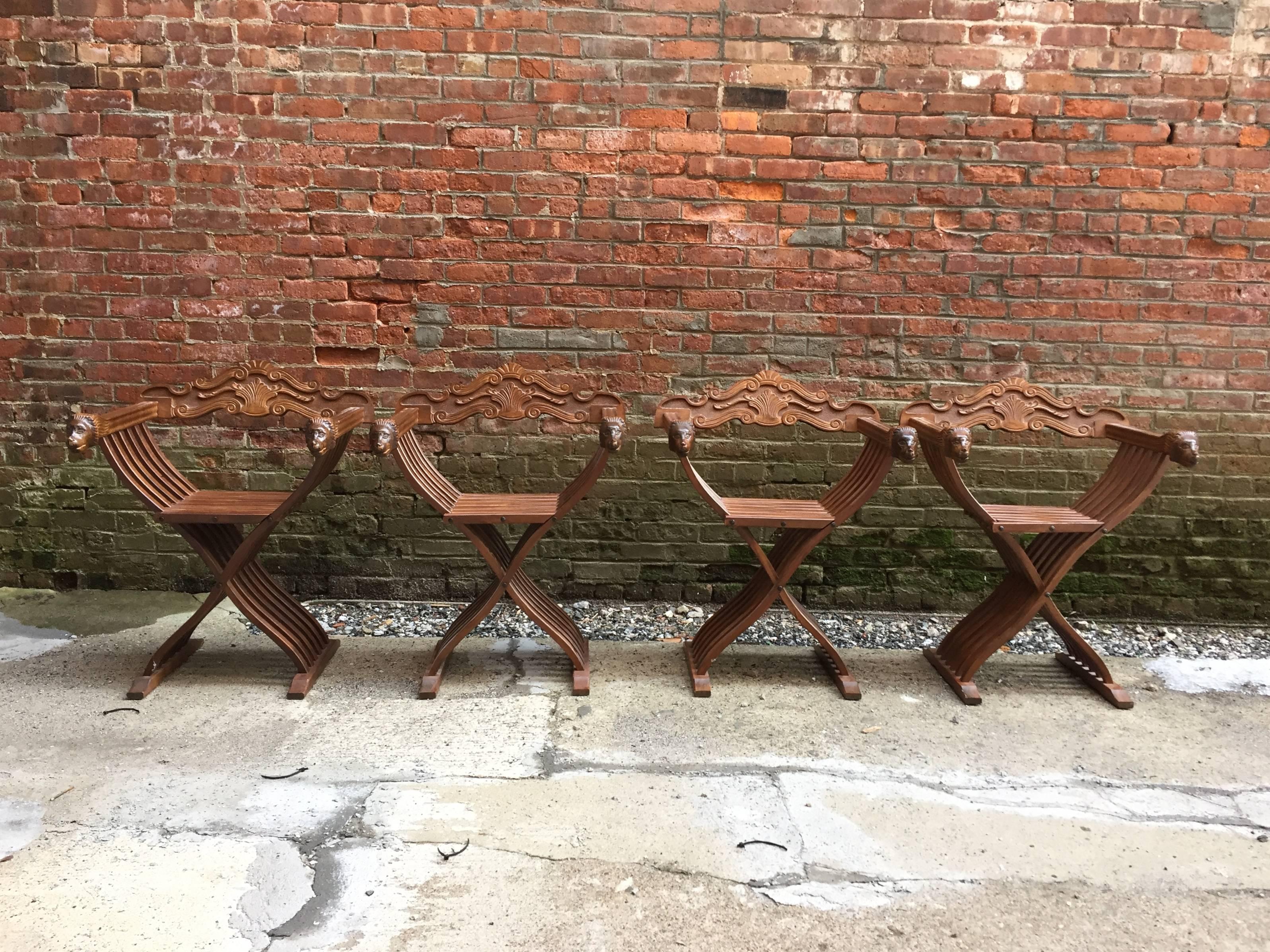 Set of four carved walnut folding Savonarola style chairs, circa 1960-1970. Very good quality. Carved lion head arms and scroll carved backs which can be removed so the chair can fold up.