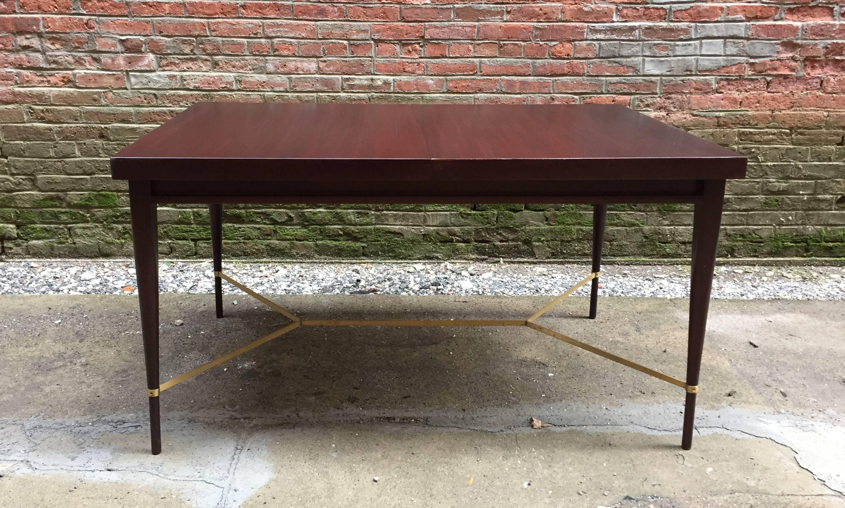 Mahogany top and tapered legs with brass stretcher base. Comes with one leaf. Wonderful, compact modern design by Paul McCobb for Calvin Group, circa 1950-1960. Old refinish that is in very good condition.

The table measures 54" closed