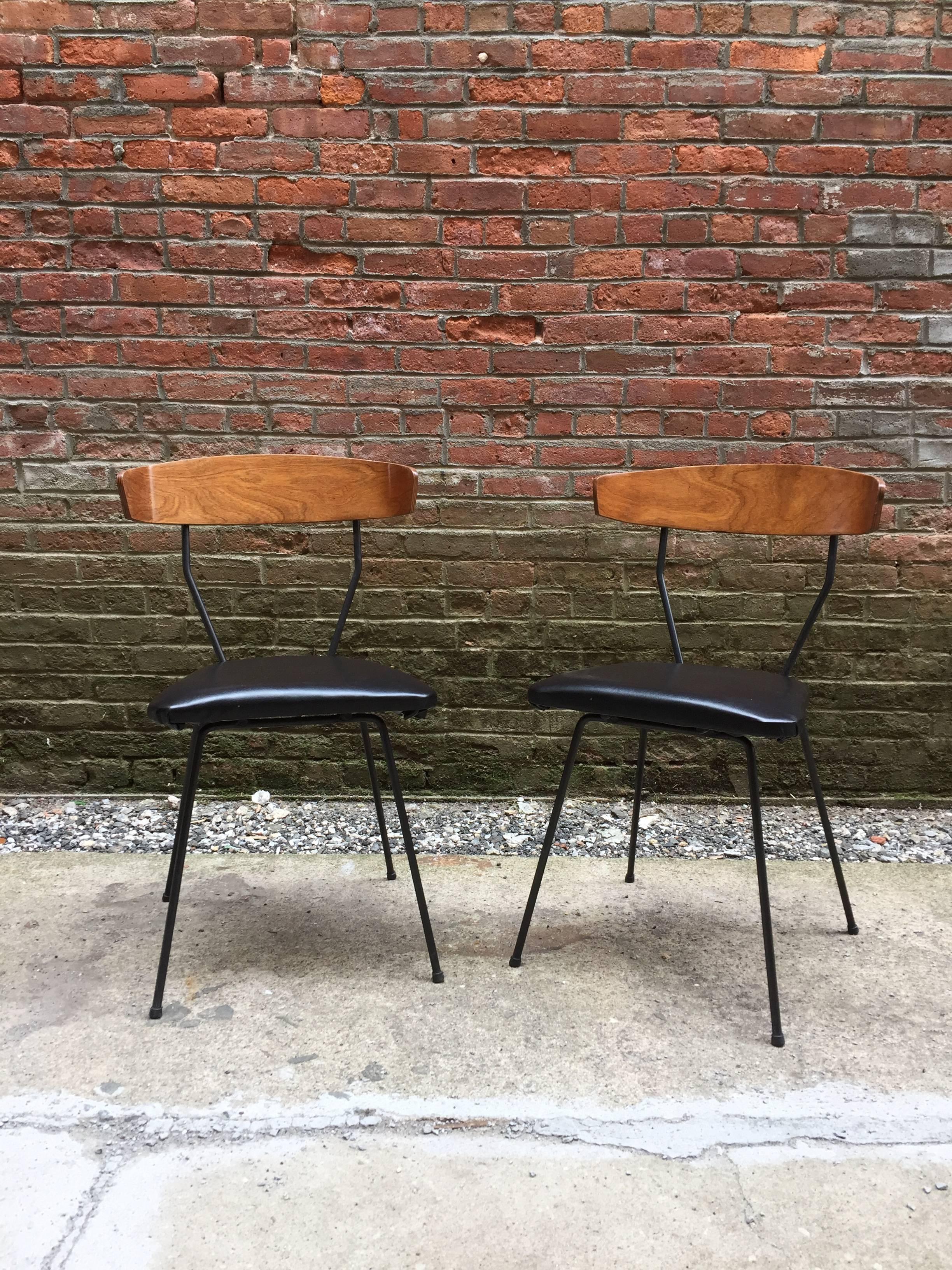The pair of chairs is a great variation to the Pascoe design; the backs are angled in and the seat cushions are flush mounted to the base. Iron bases with bentwood walnut veneer back supports.