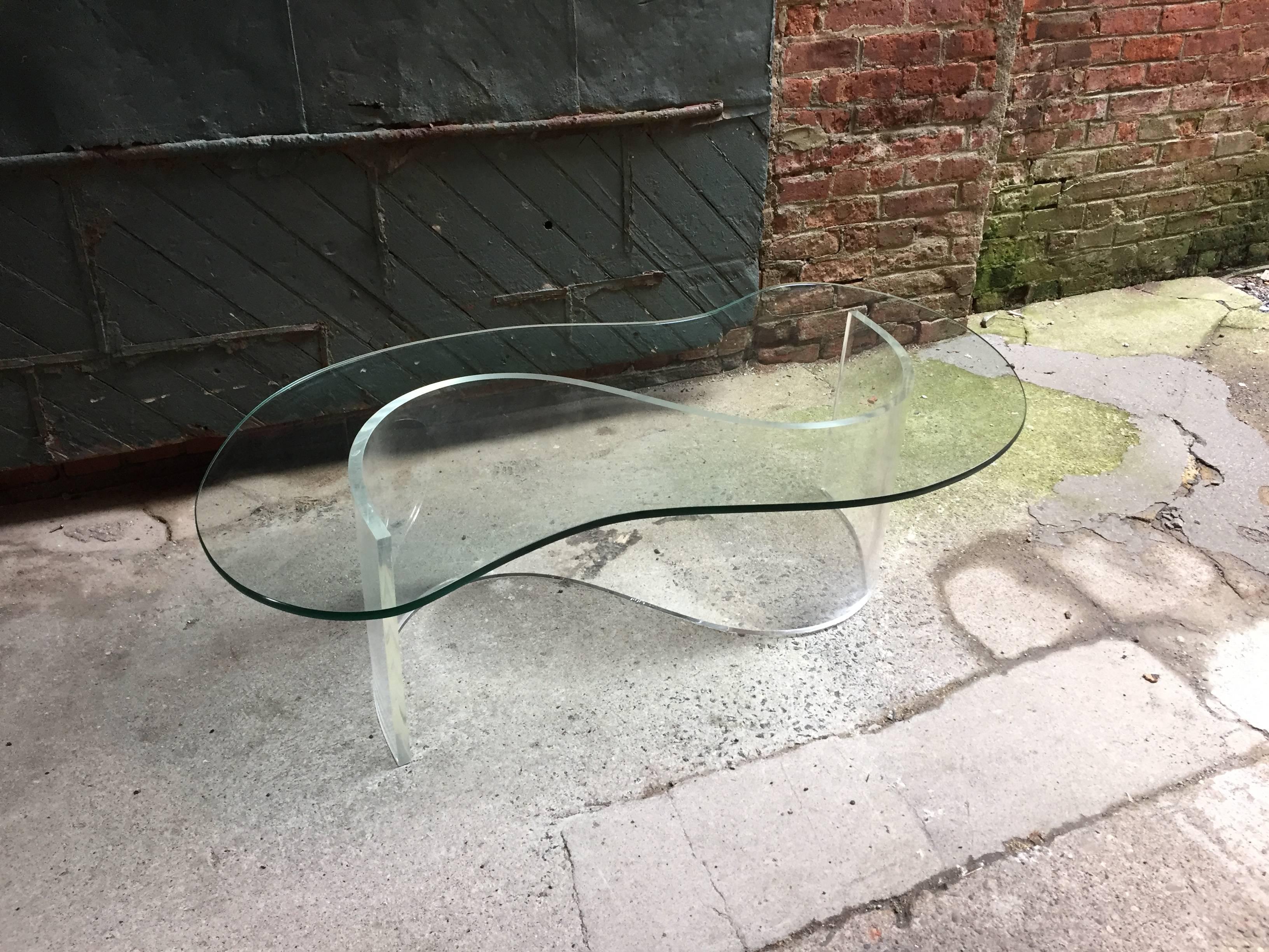Free-form glass top on S shaped acrylic/Lucite base, circa 1970. Glass top measures 49" x 27.5" x .5" high.
