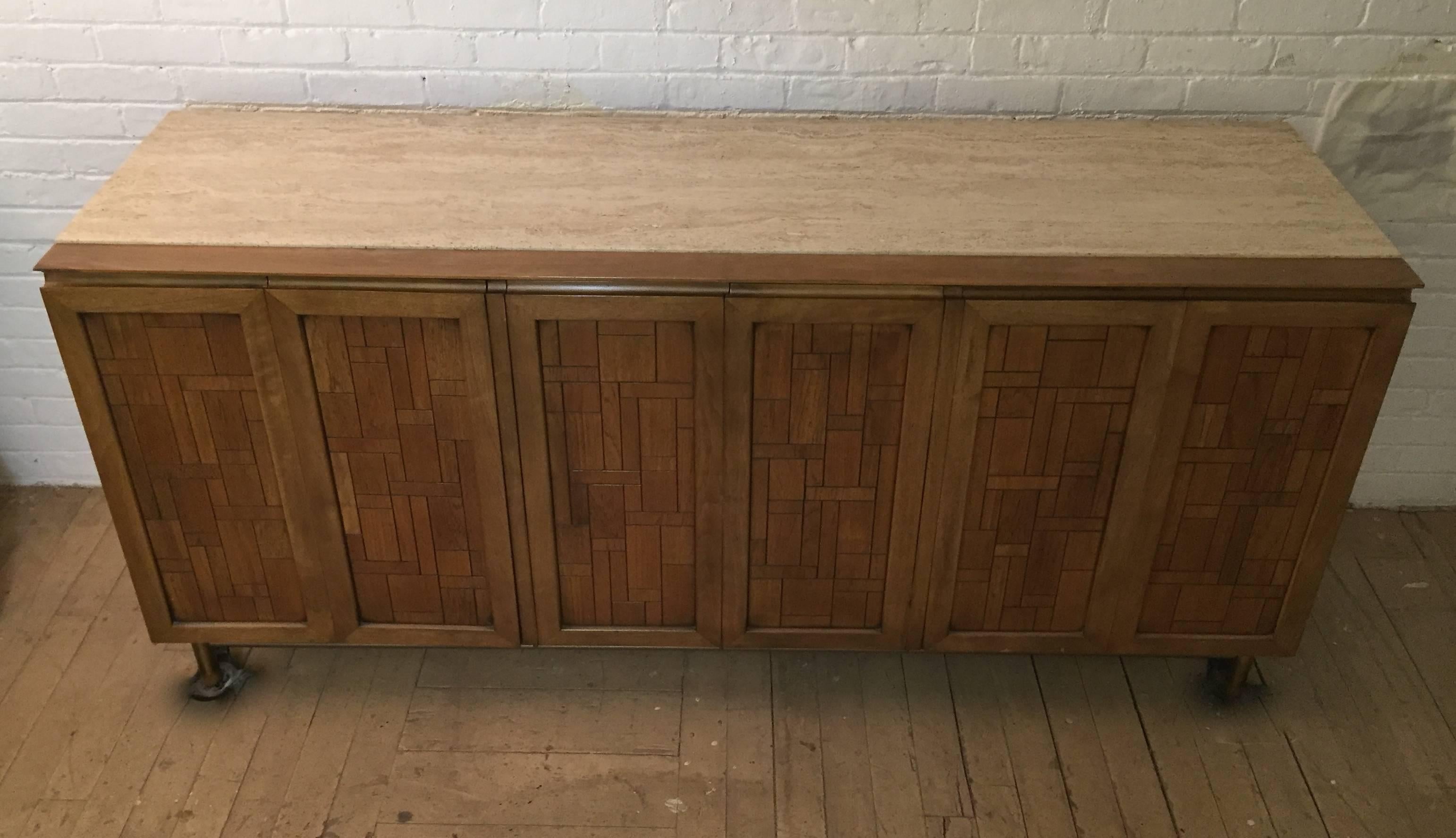 Bert England design for Johnson Furniture Company. Travertine top, eight drawers and two shelf compartments hidden by six doors. Supported by alloy metal legs ending with wood feet, circa 1960-1970.