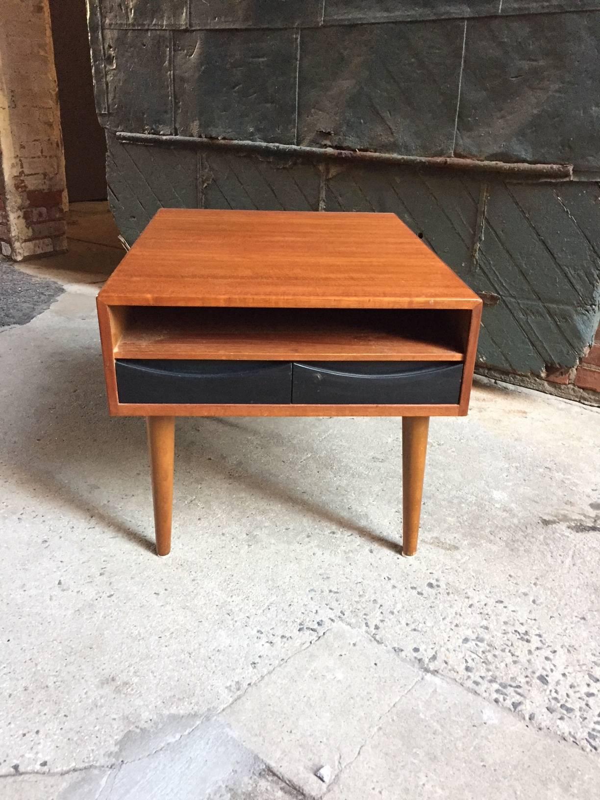 Slender two-drawer teak end table. Unsigned. Two small black lacquered drawer fronts, circa 1960.

Good condition. The drawers are lined with foam.