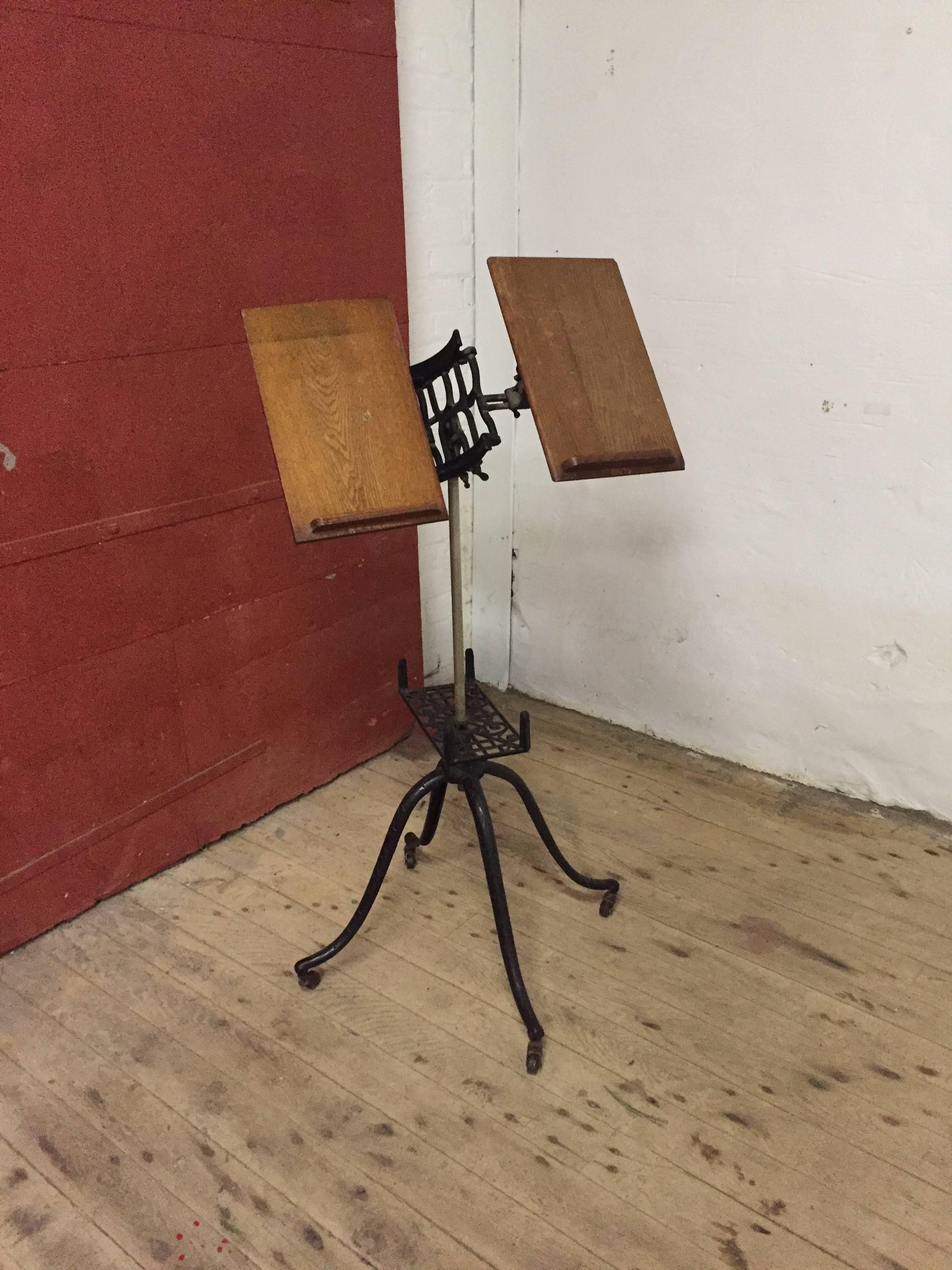 Fully adjustable iron and oak book stand, circa 1900. Beautiful wrought iron base and hardware with tilting oak panels for large and small books. Original finish. 

Full extended height is approximately 44". The base is 23" x 23".