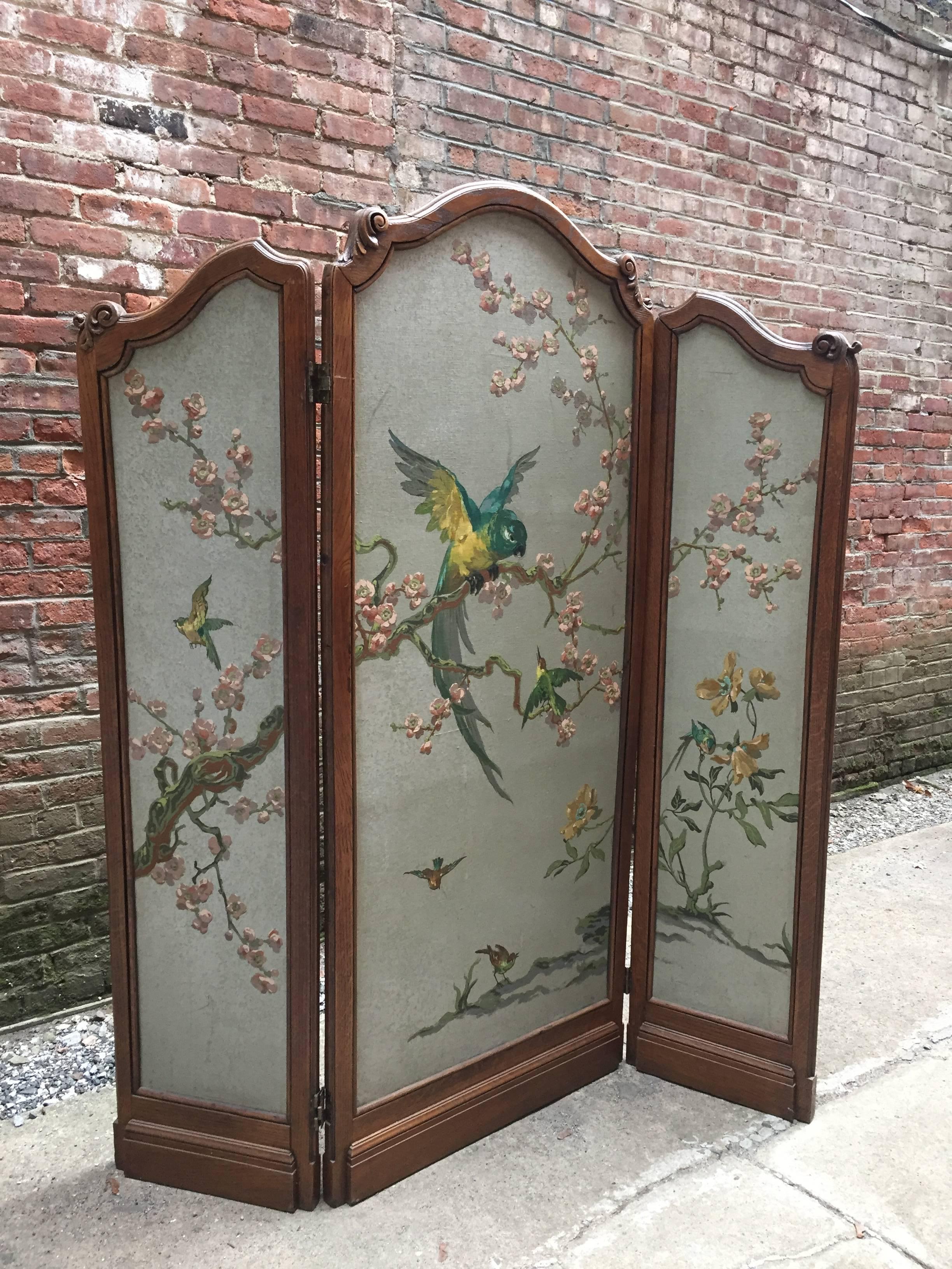 Masterfully hand-painted three part room divider with carved oak frame. Cherry Blossoms and birds decorate one side and verso is adorned with butterflies. The 1930s Japanese inspired screen is a statement for any room. Colorful and