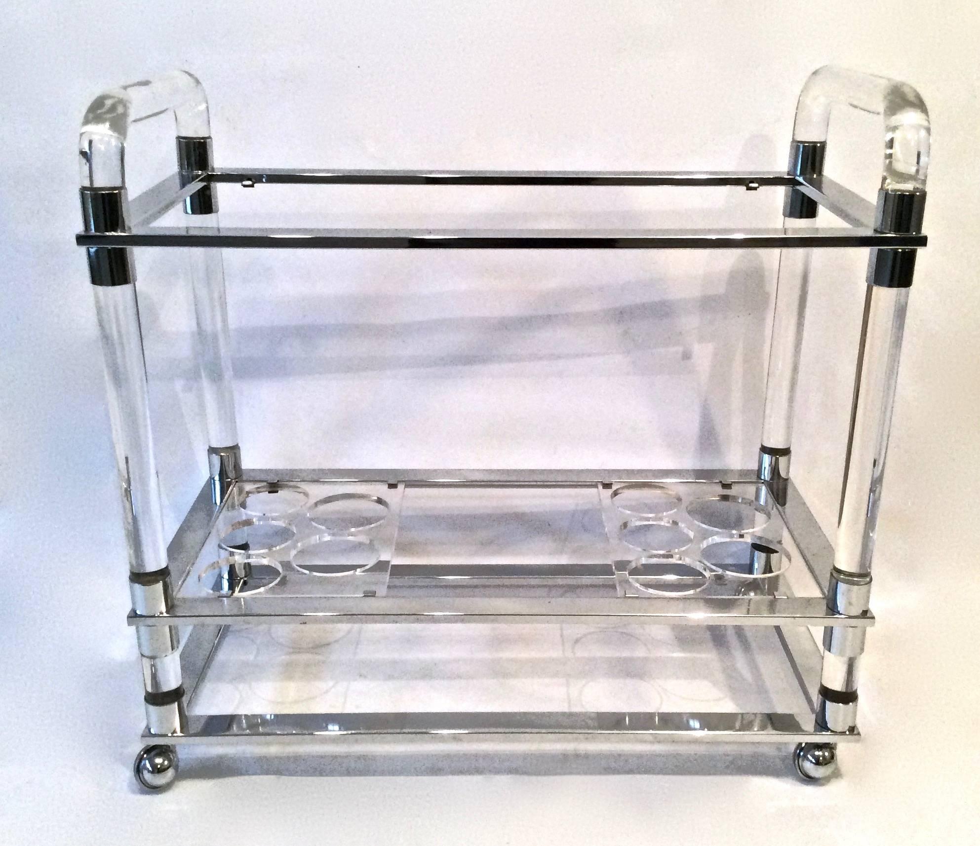 Manner of Milo Baughman glass, chrome and Lucite bar cart on wheels. Thick, clear and chunky Lucite frame, trimmed with bands of chrome around the top glass and bottom tier shelves. Lower tier retains original clear acrylic bottle holder inserts.