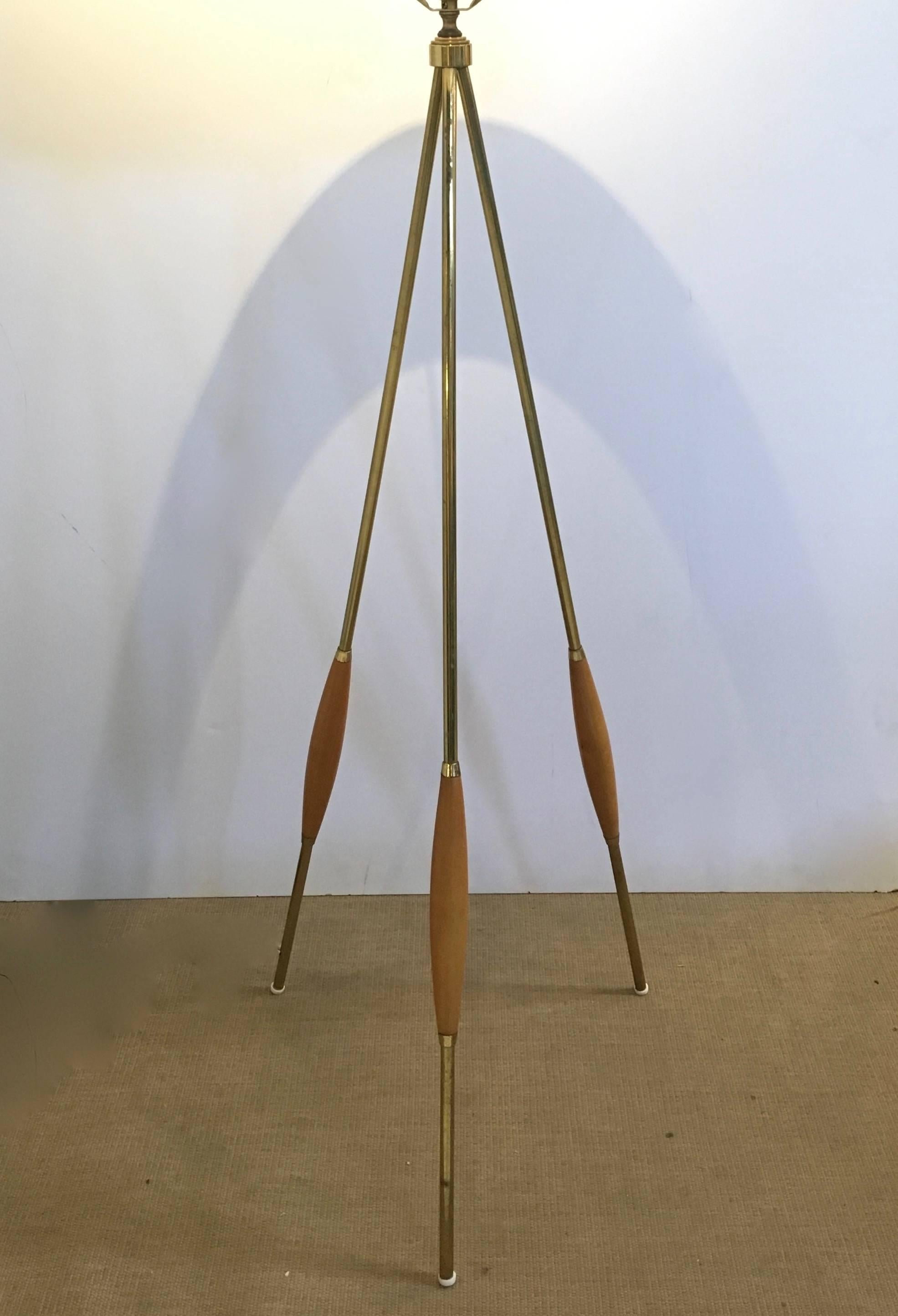 This is a vintage Mid-Century tripod floor lamp attributed to Gerald Thurston, for Lightolier in the 1950s, USA. It features a brass finish base and walnut accents on the legs. The original integrated harp is intact, newly rewired, with new, period