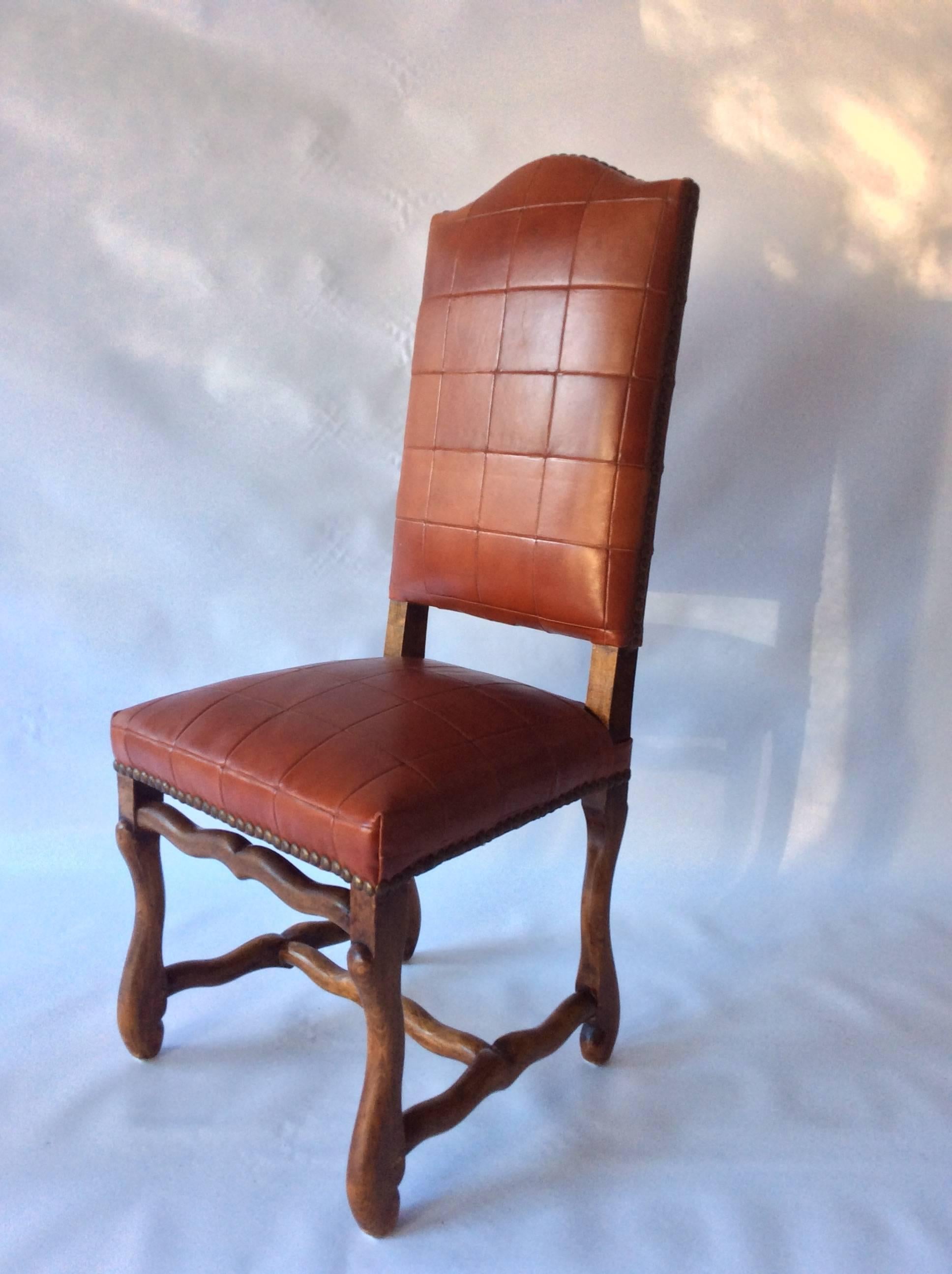 A custom upholstered, set of six, 19th century continental dining chairs with Os de Mouton peg joined bases, updated in fabulous stitched oxblood patchwork leather by Todd Hase and aged brass nailhead trim. Excellent condition overall.